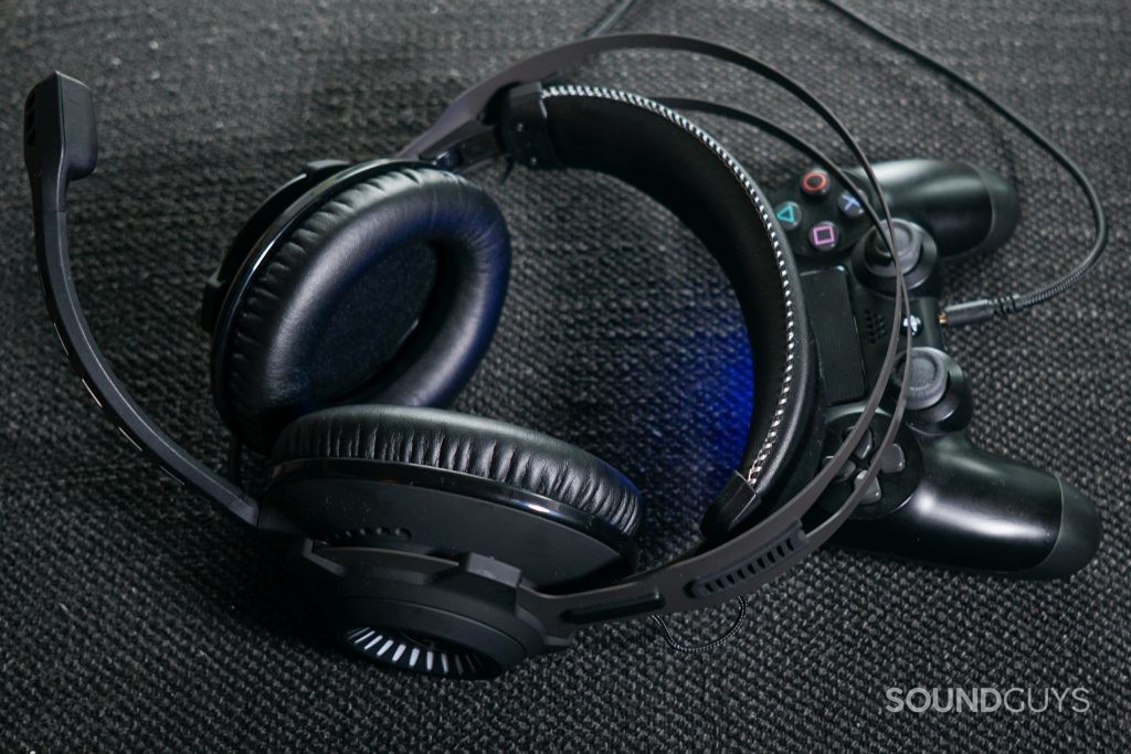 The HyperX Cloud Revolver + 7.1 lays on a PlayStation DualShock 4 controller into which it is plugged.