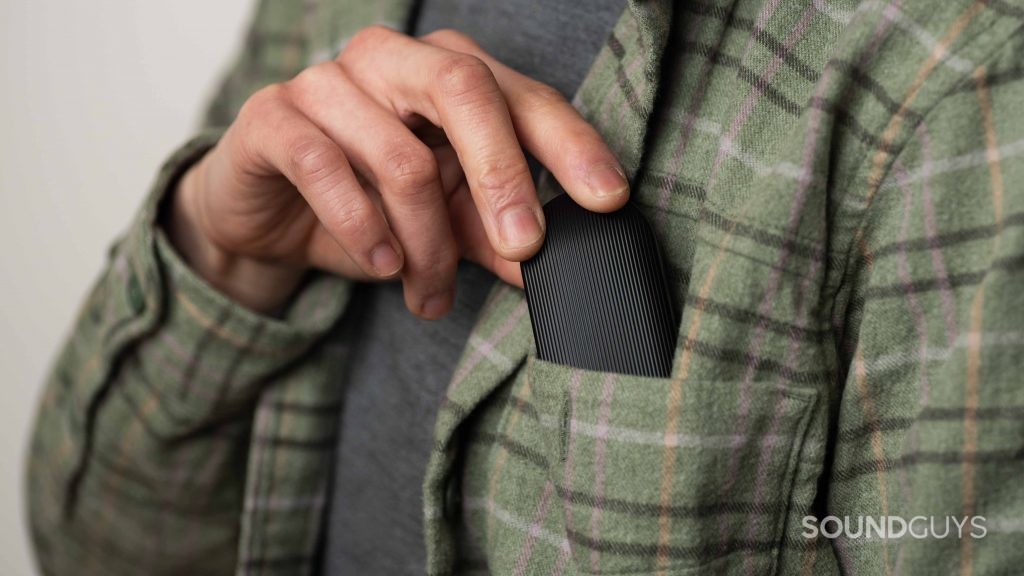 A hand inserts the Mobvoi Earbuds Gesture case into a breast pocket.