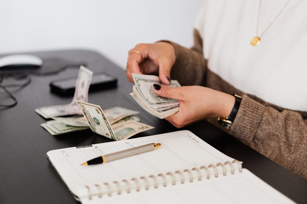 Accounting with dollar bills and a pen and paper on a desk.