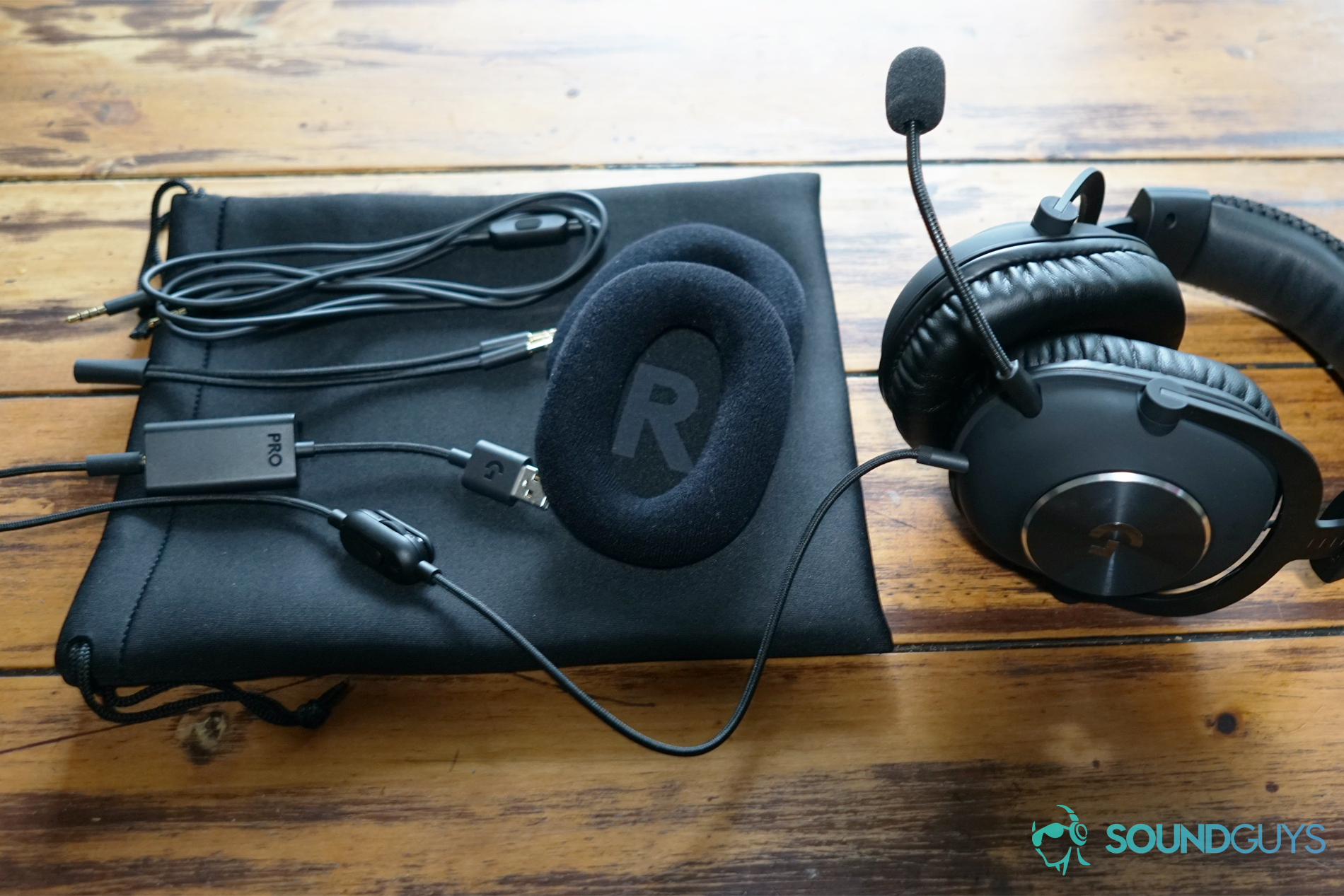 The Logitech G Pro X sits on a table next too all the different attachments it comes with.