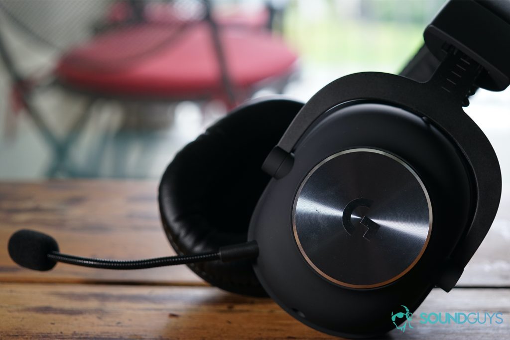 The Logitech G Pro X lays on a wooden table in front of a window and some outdoor chairs.