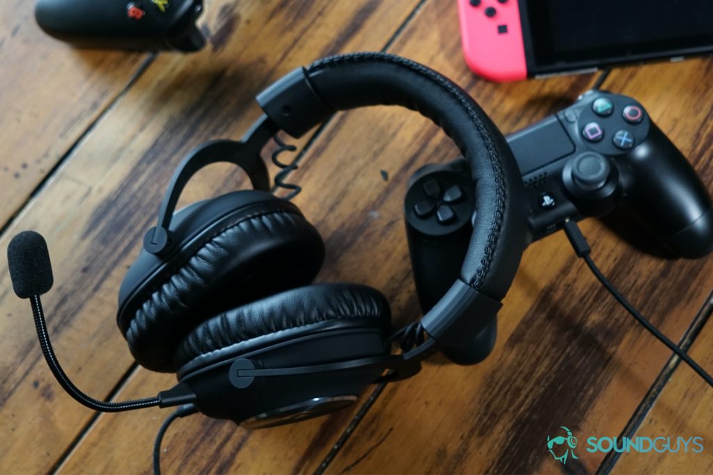 The Logitech G Pro X lying on a wooden table next to controllers for the Playstation 4 and Xbox One, as well as a Nintendo Switch Console