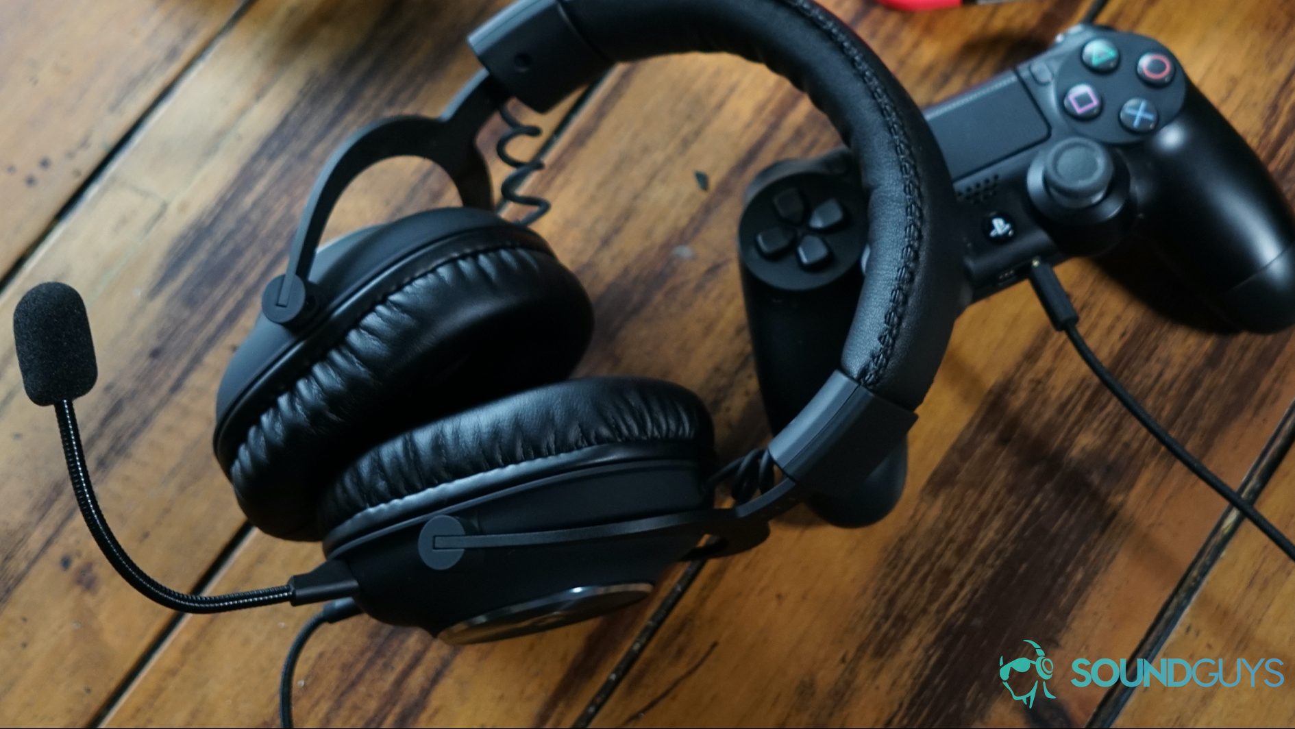 The Logitech G Pro X lying on a wooden table next to controllers for the Playstation 4 and Xbox One, as well as a Nintendo Switch Console