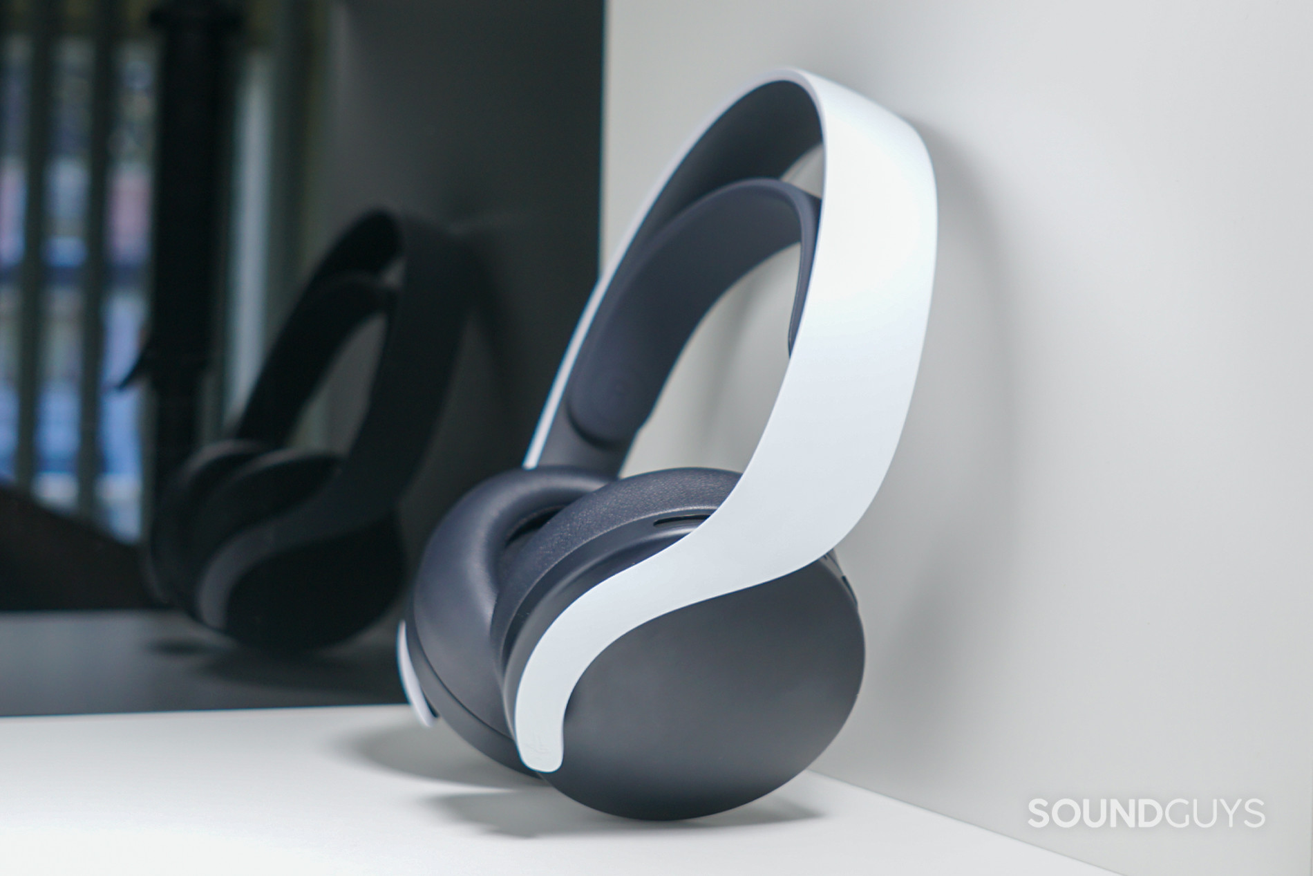 The Sony Pulse 3D wireless headset sits on a white shelf in front of a reflective black panel.