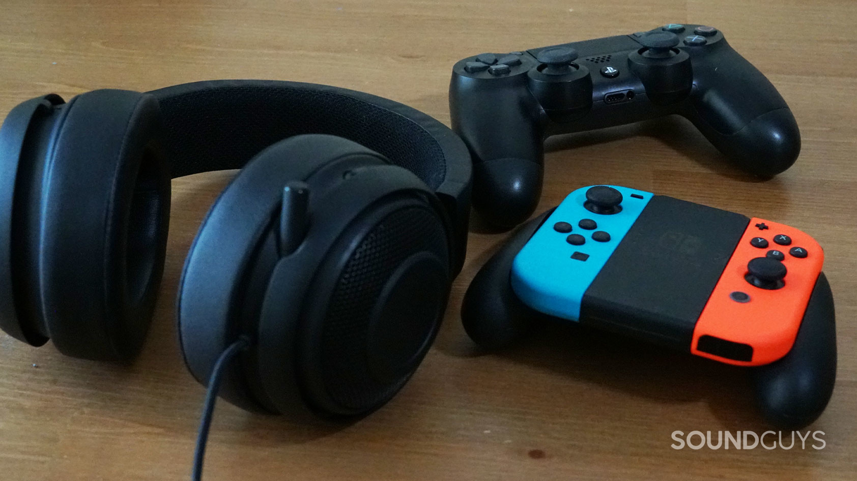 The Razer Kraken V2 Pro gaming headset next to a Nintendo Switch and PlayStation 4 controller.