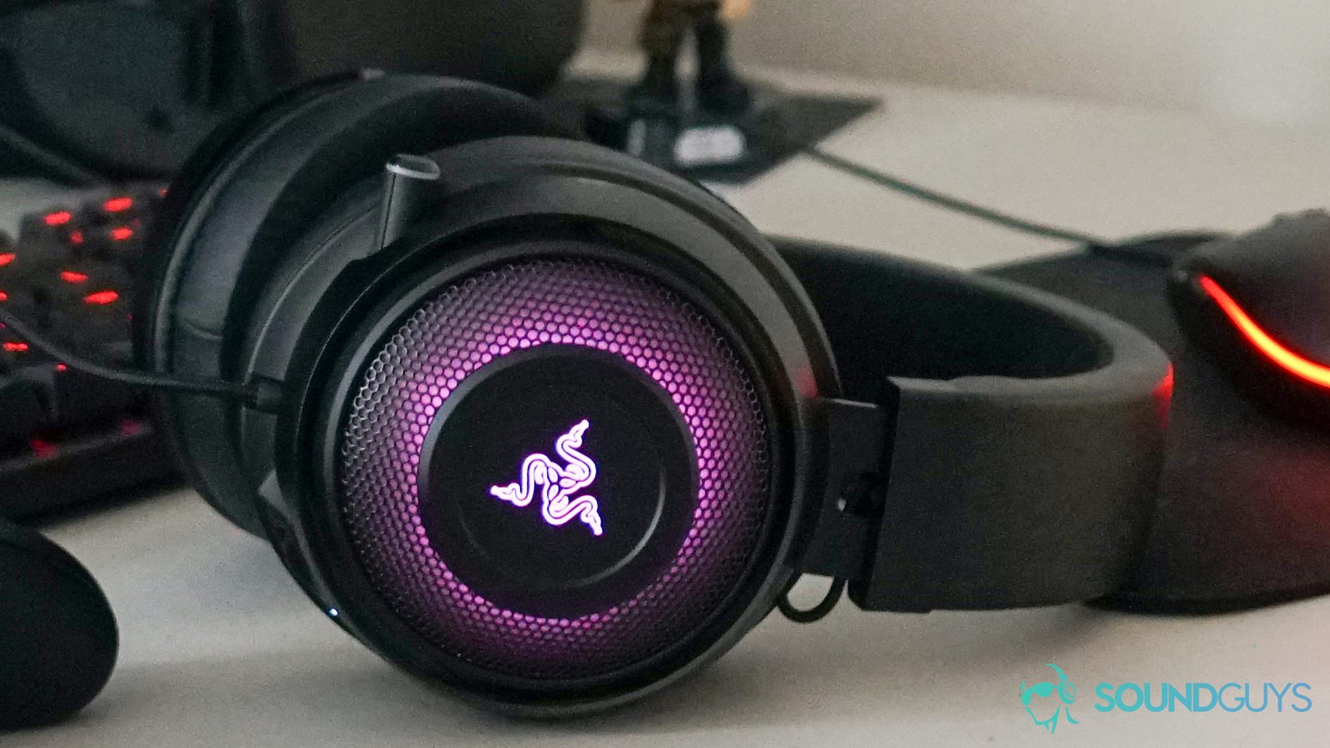 The Razer Kraken Ultimate lays on a desk in front of a Logitech mechanical gaming keyboard and gaming mouse, a Han Solo figure, and a Viewsonic computer monitor.