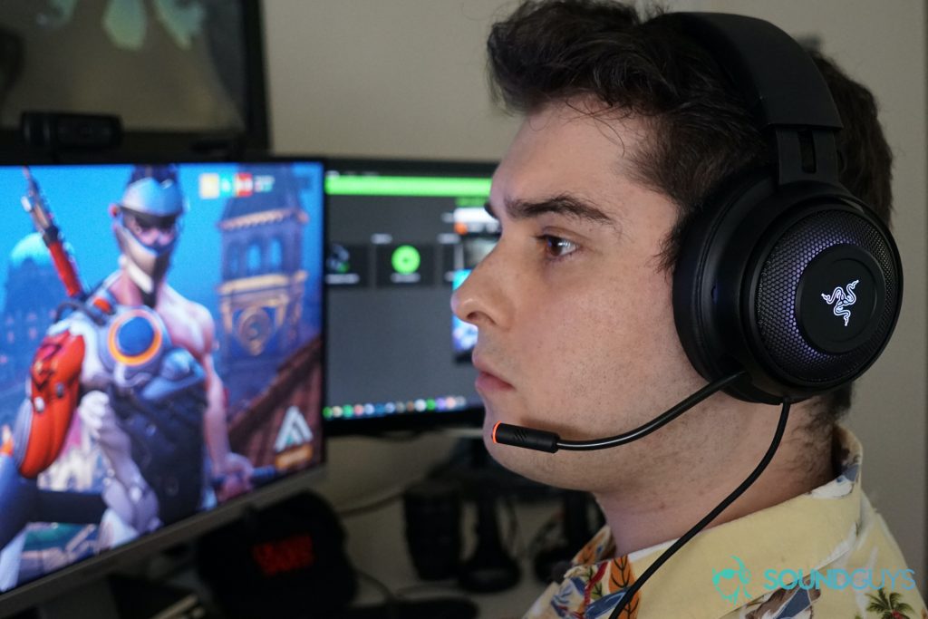 A man wears the Razer Kraken Ultimate sitting at a computer running Overwatch and Razer Synapse