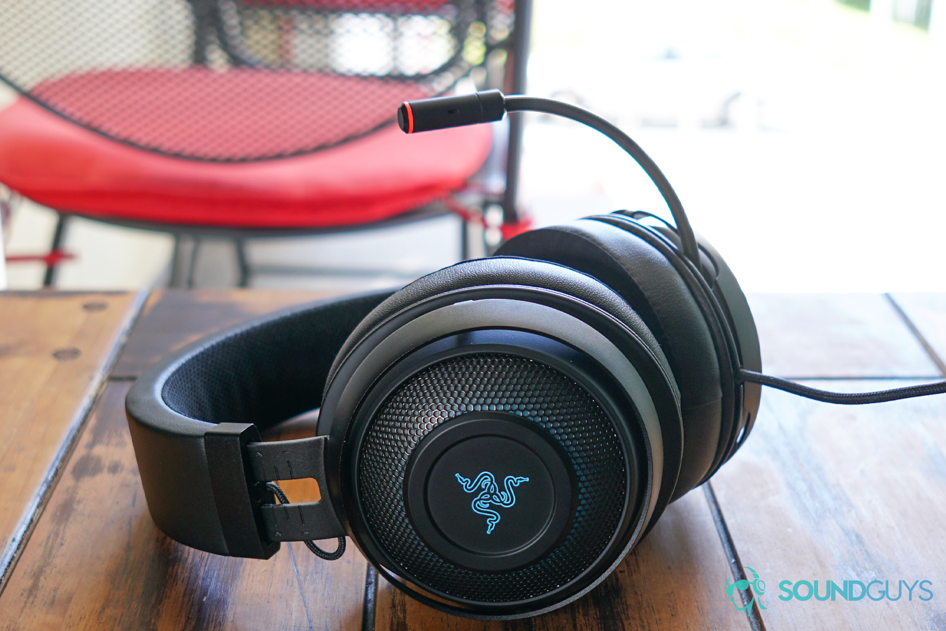 The Razer Kraken Ultimate sits on a wooden table in front of a balcony with tables and chairs.