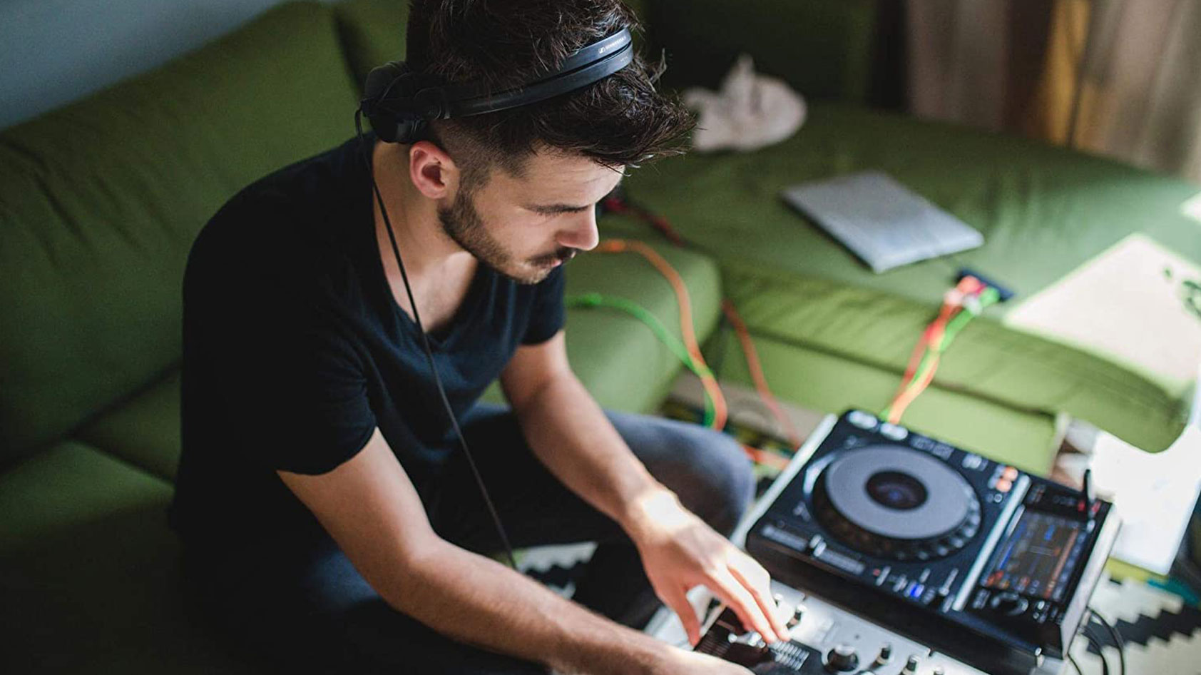 A man wears the Sennheiser HD 25 on-ear headphones while he uses a digital turntable.