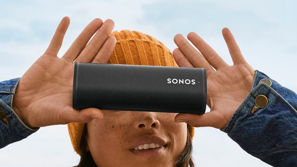 A woman holds the Sonos roam in front of her face.