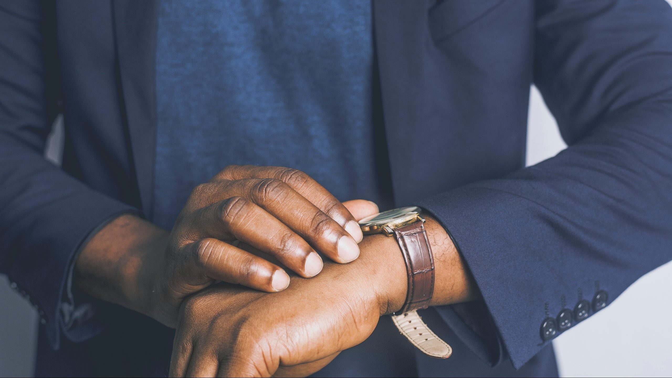 standing-man-waits-pexels-jeffrey-paa-kwesi-opare A man stands and looks at his watch as if waiting for something.