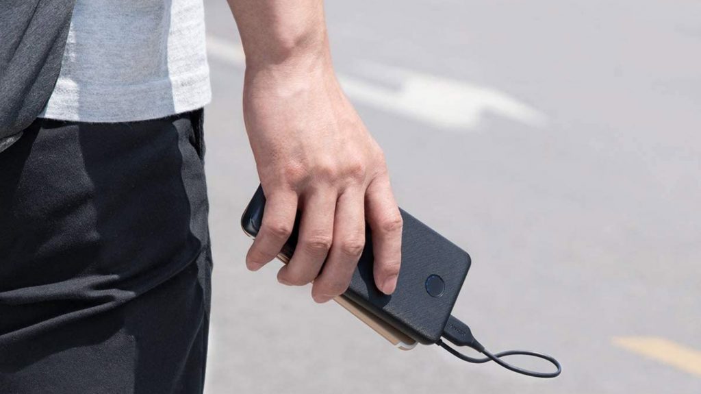 A man holds the Anker PowerCore Slim portable battery pack in front of a street.
