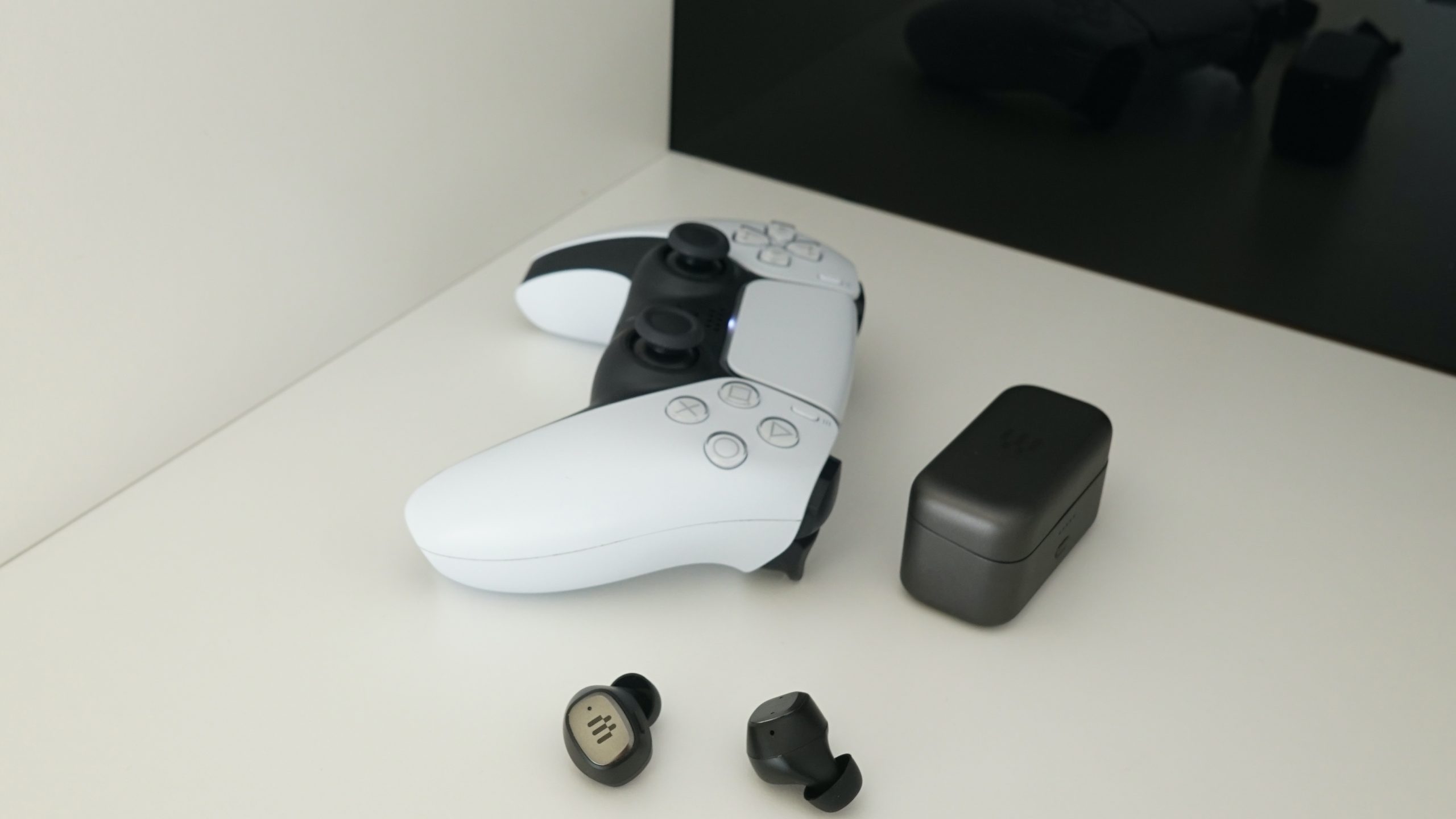 The EPOS GTW 270 Hybrid lays on a shelf next to a PlayStation DualSense controller.
