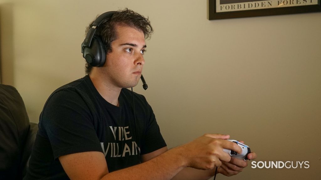 A man wears the EPOS H3 gaming headset plugged into a PlayStation 5 DualSense controller.