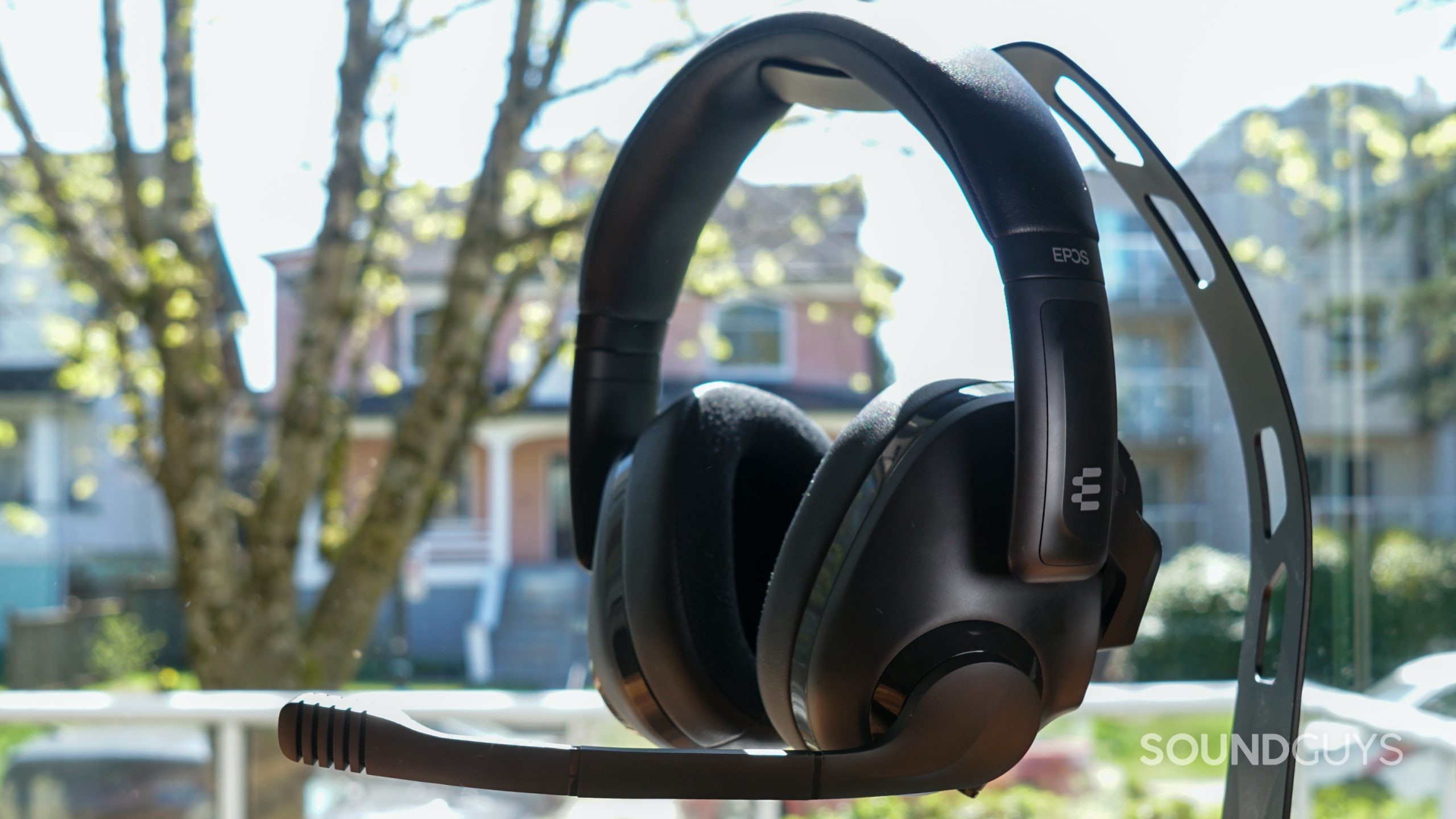 The EPOS H3 gaming headset sits on a stand in front of a window.