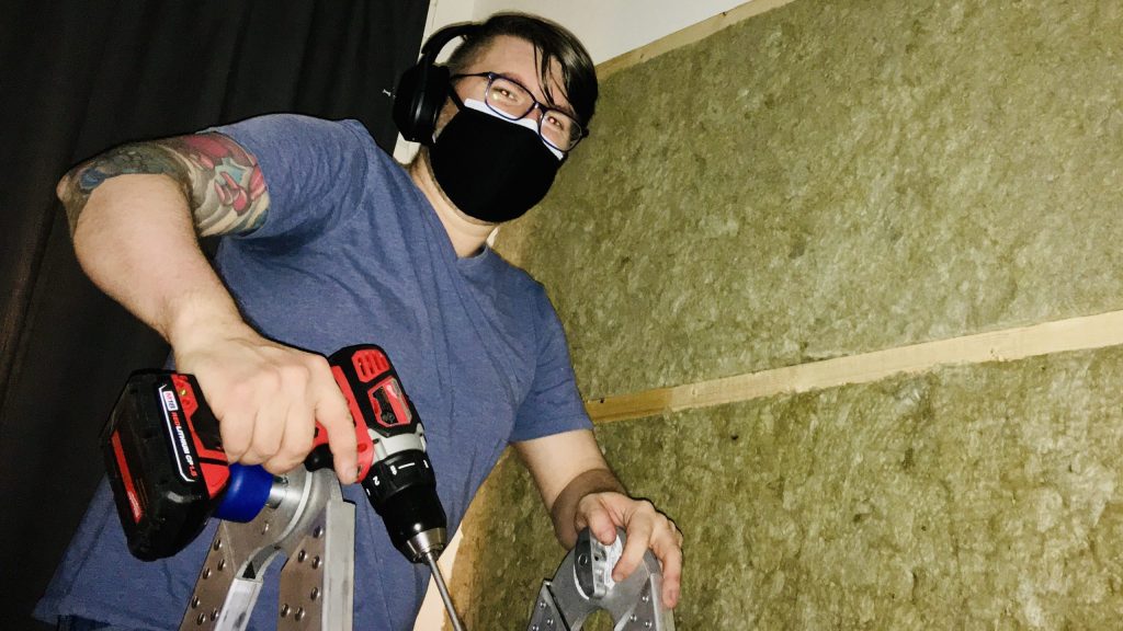 Chris Thomas on a ladder installing acoustic insulation.