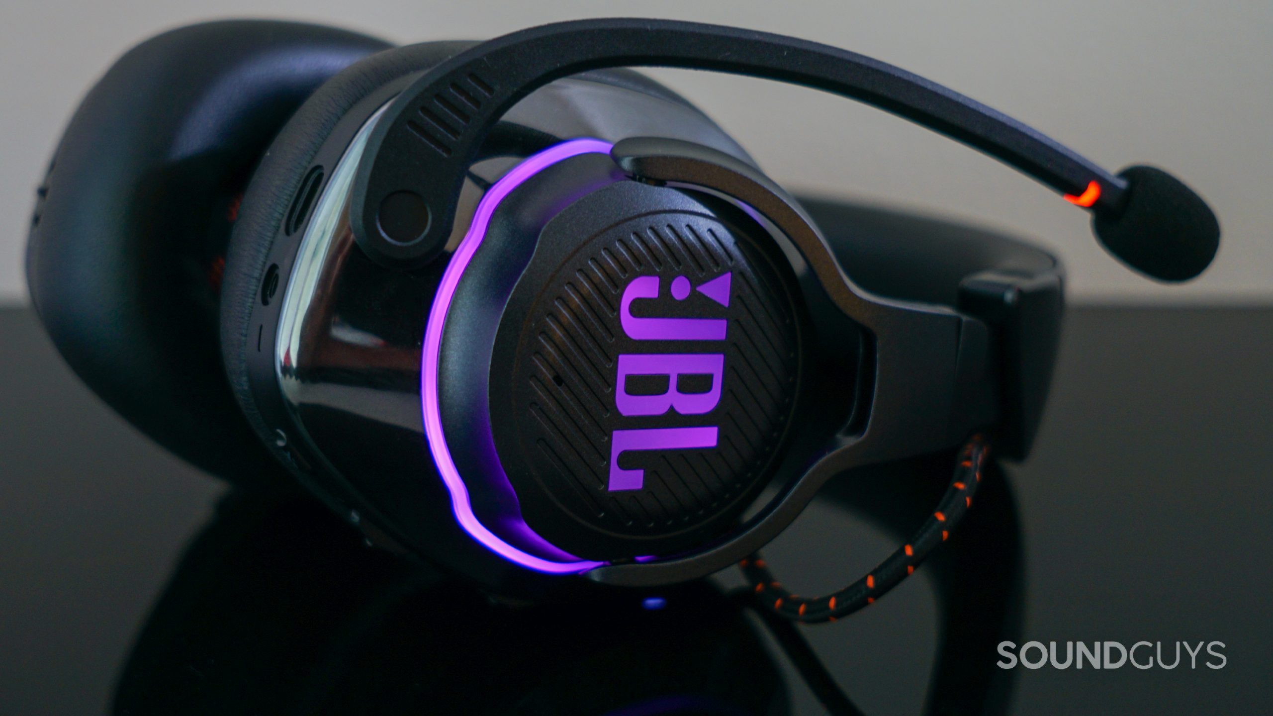 The JBL Quantum 800 gaming headset lays on a black reflective surface