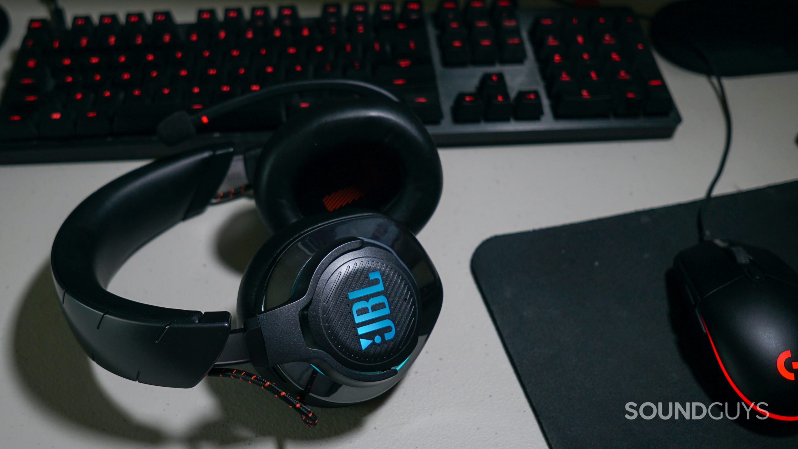 The JBL Quantum 800 lays on a desk next to a Logitech gaming keyboard and mouse.