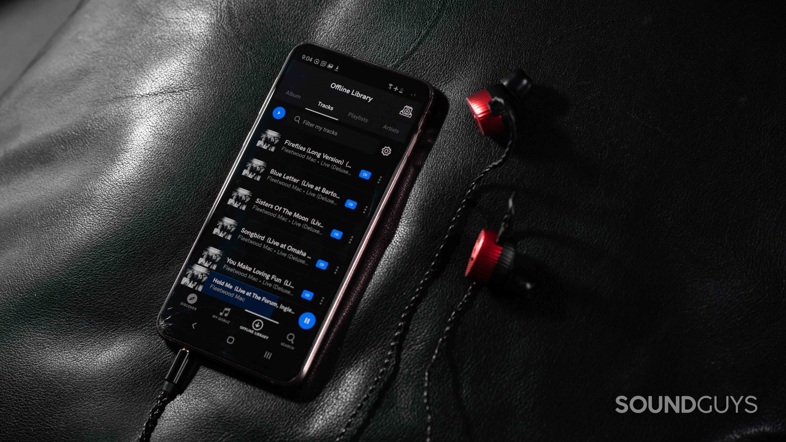 The Qobuz music streaming service app's Offline Library page open on a Samsung Galaxy S10e smartphone next to a pair of Massdrop x Noble Kaiser 10 IEMs.