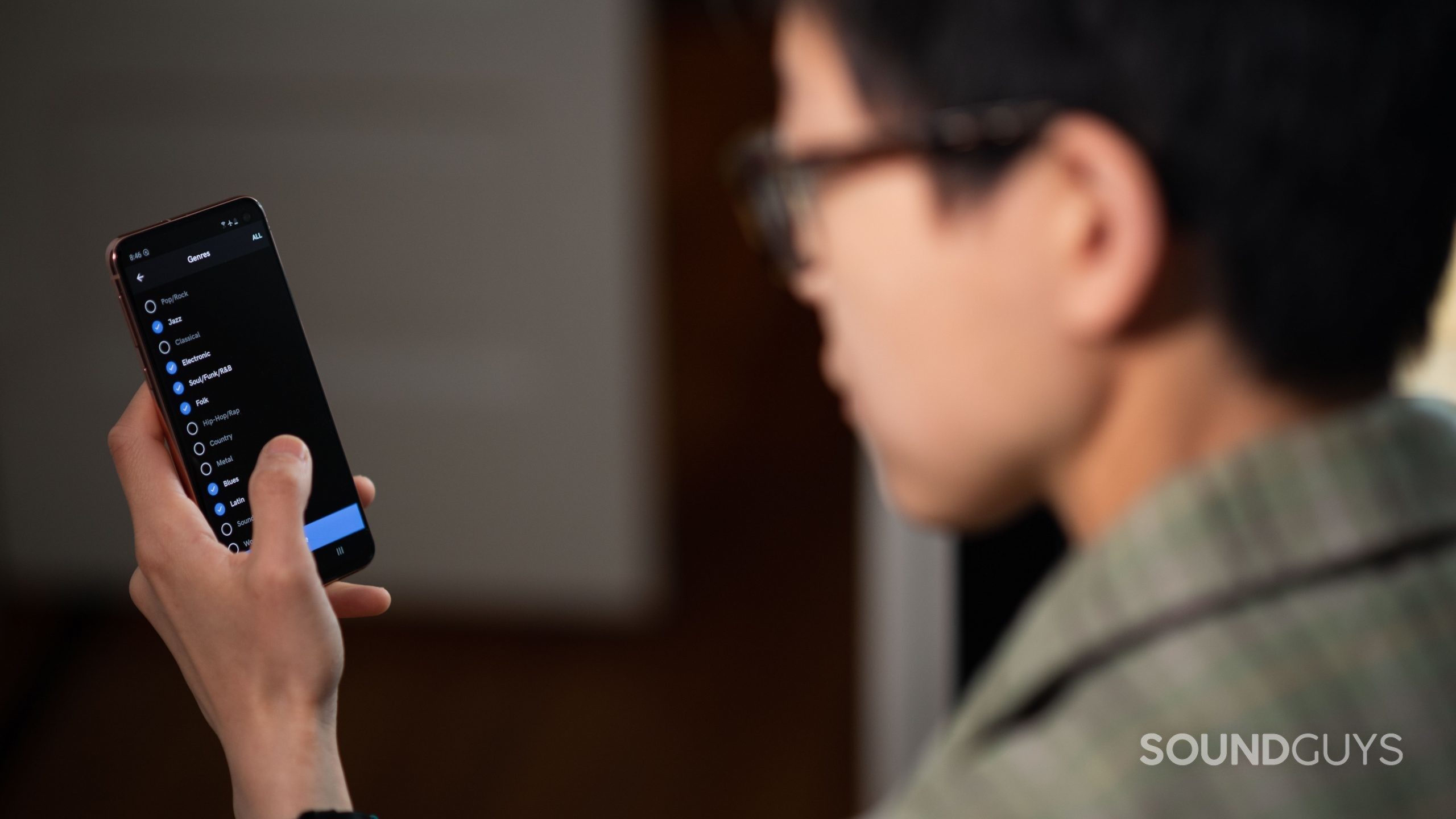 A woman navigates through the Qobuz mobile app Genre page.