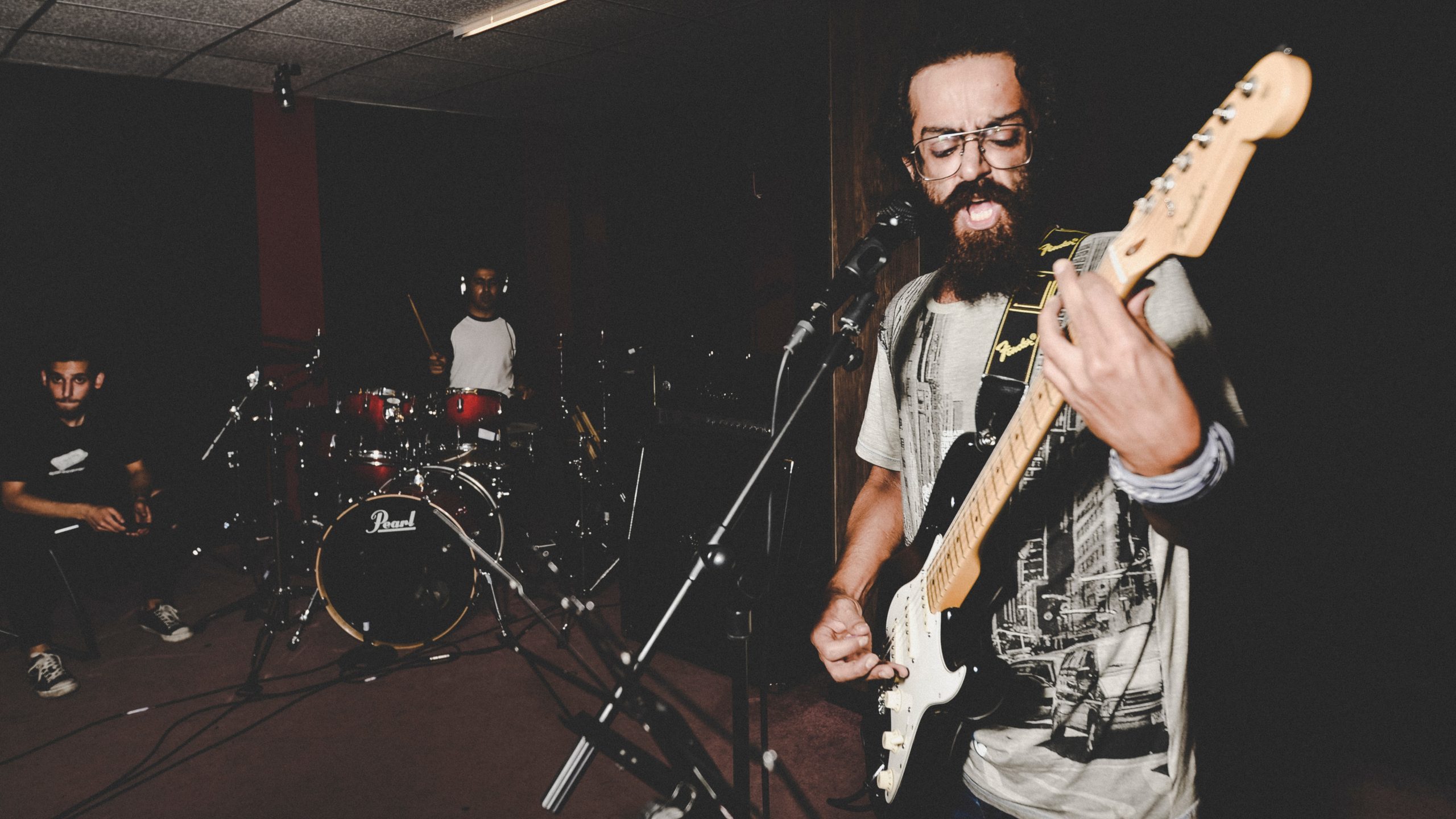 sam-moqadam-6T-i3WfjmBE-unsplash A three-person rock band rehearses in a studio.