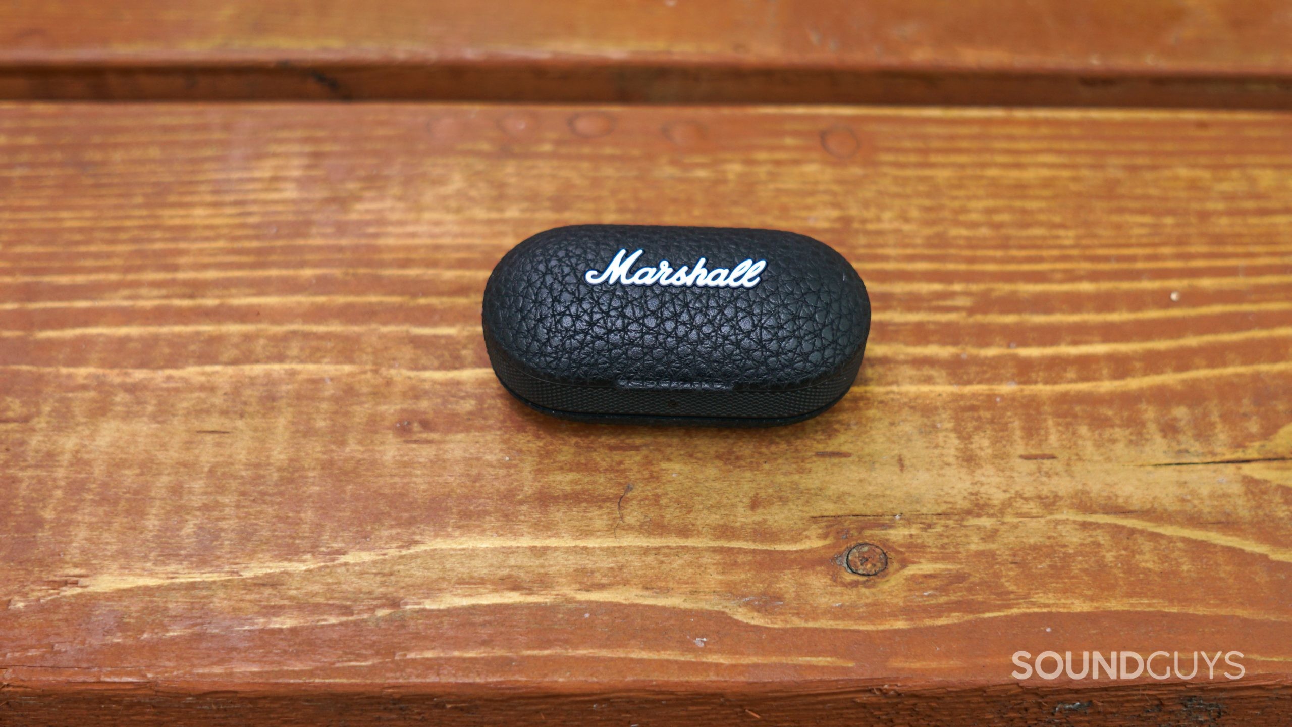 Marshall Mode II case closed The charging case for the Marshall Mode II True Wireless Earbuds sits closed on a wood surface.