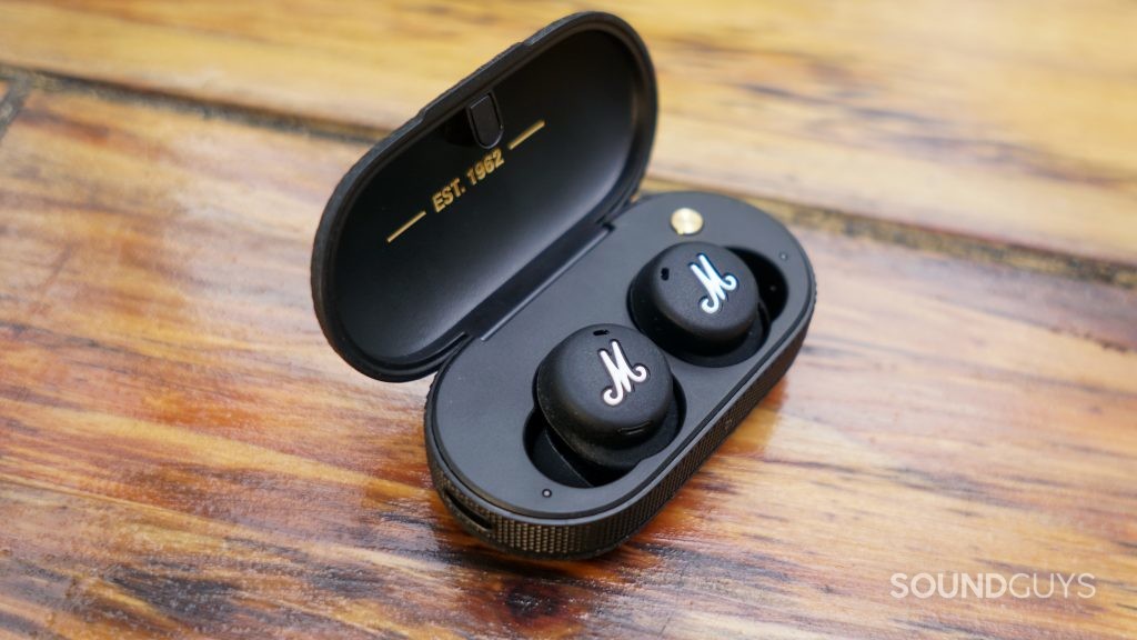 A close up shot of the Marshall Mode II true wireless earbuds in their charging case on a wooden table.