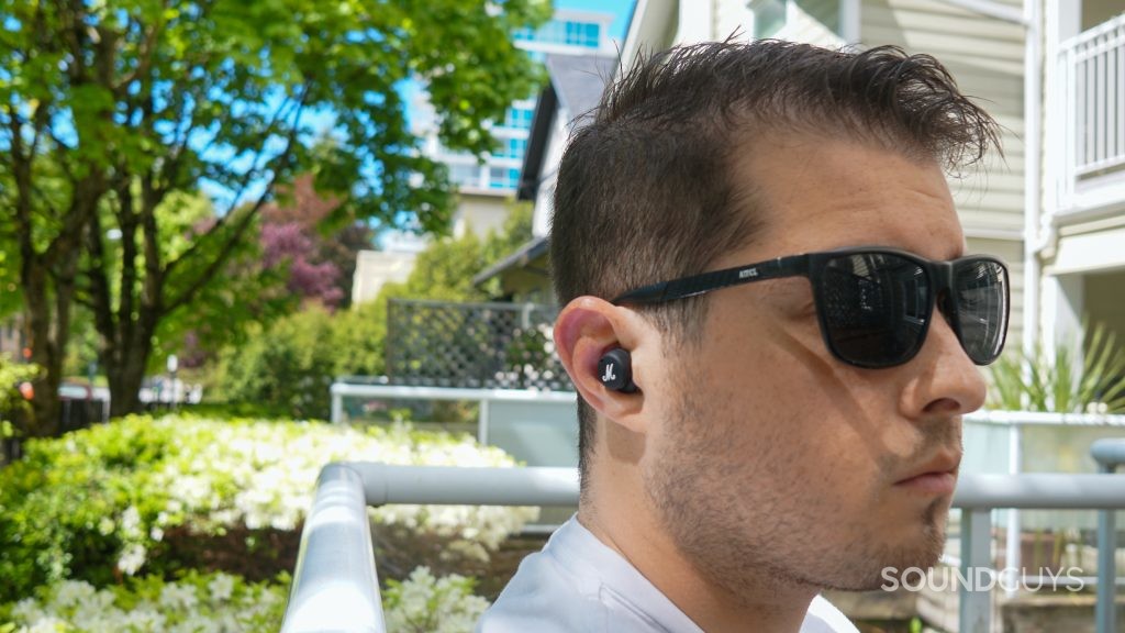 A man sits outside wearing sunglasses and the Marshall Mode II true wireless earbuds.
