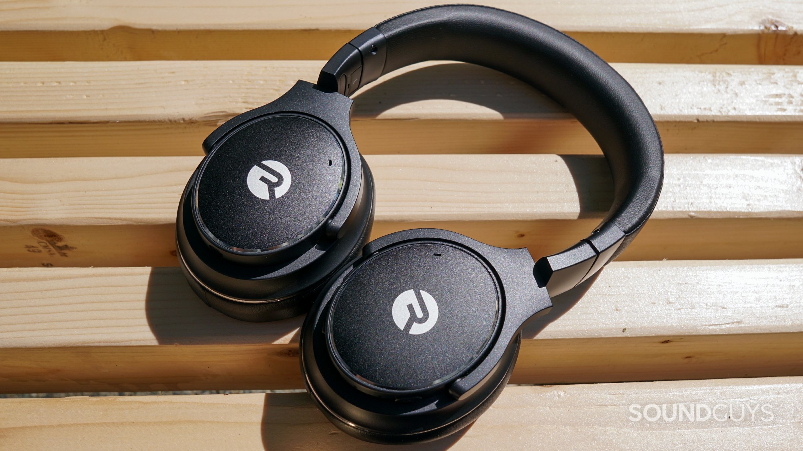 The Raycon Everyday Headphones lay on a wooden bench. 
