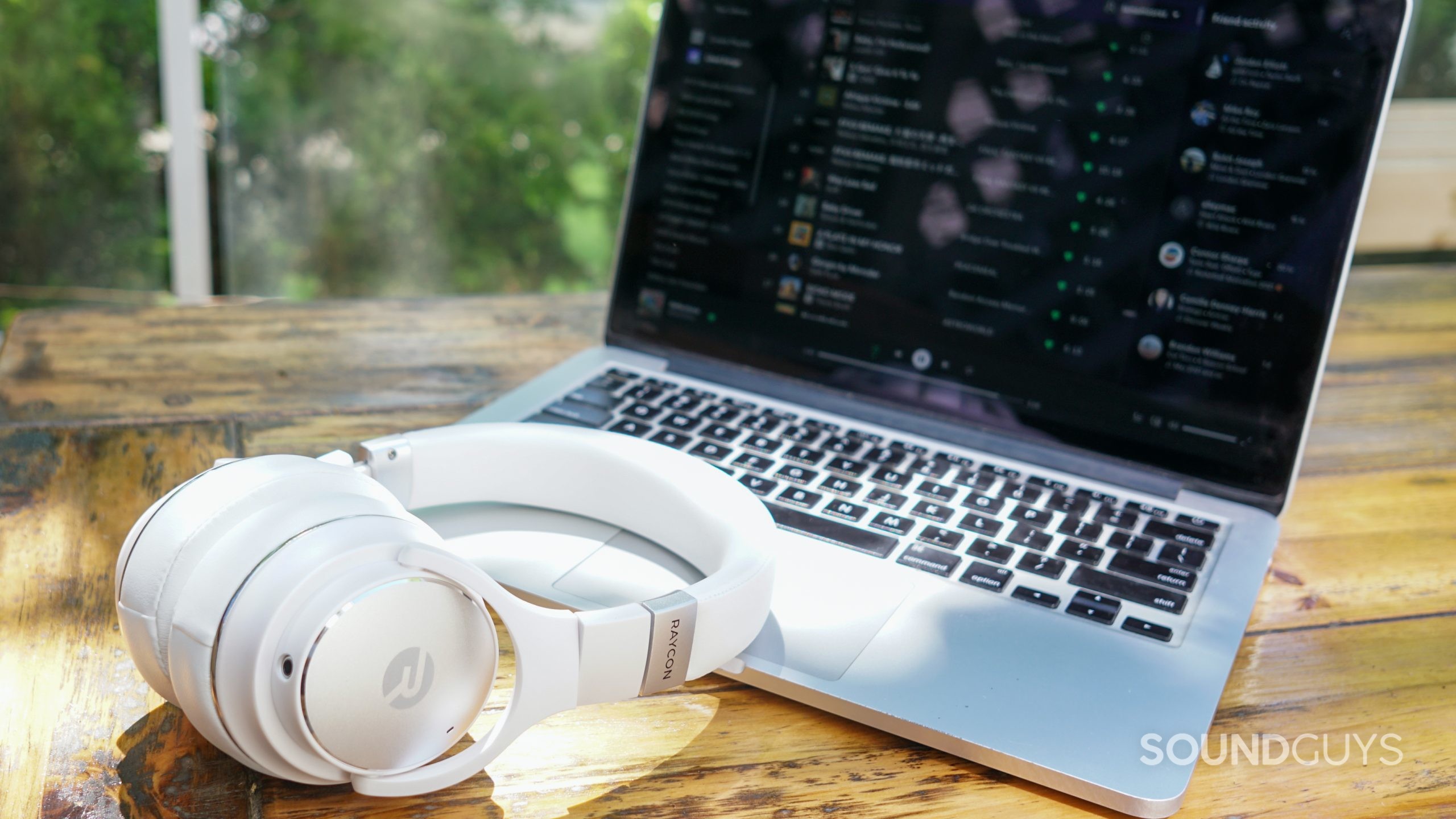 The Raycon Everyday Headphones lay on an Apple MacBook Pro, to which it is connected.