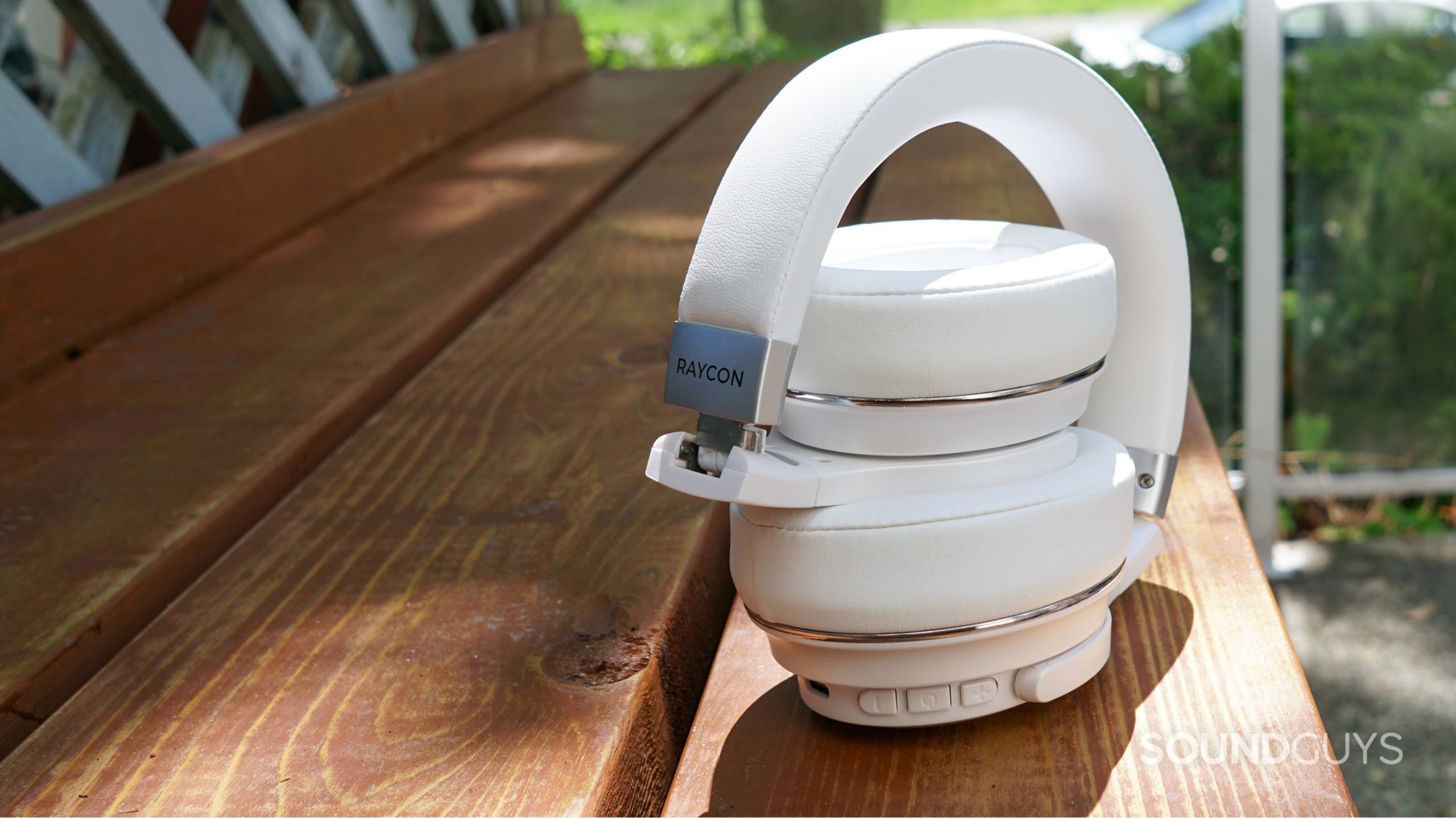 The Raycon Everyday Headphones sit folded up on a wooden surface.