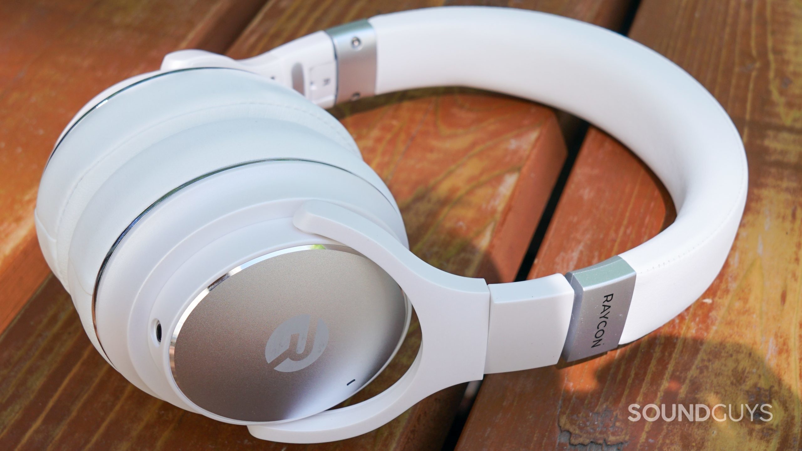 Raycon Everyday Headphones laying side shot The Raycon Everyday Headphones lays on a wooden surface.
