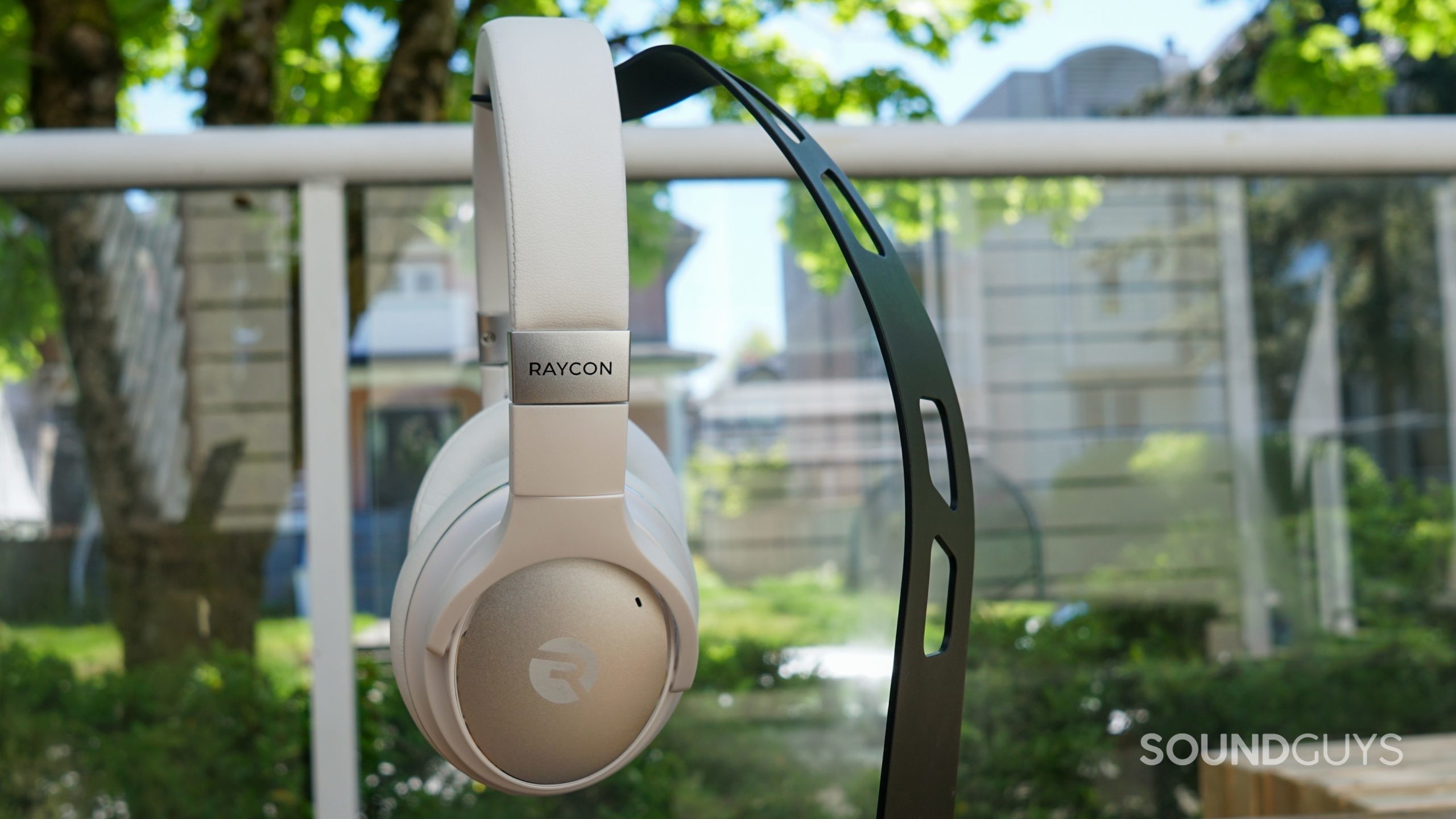 The Raycon Everyday Headphones on a headphone stand against a backyard.