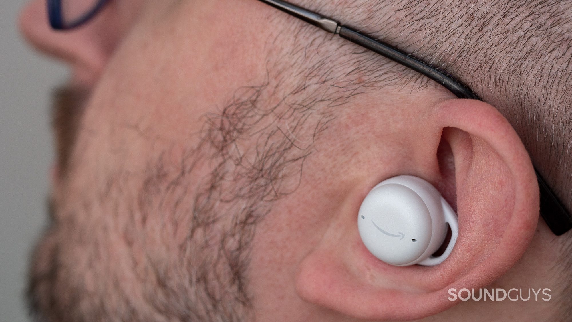 A man wears the left earbud of the Amazon Echo Buds (Gen. 2).