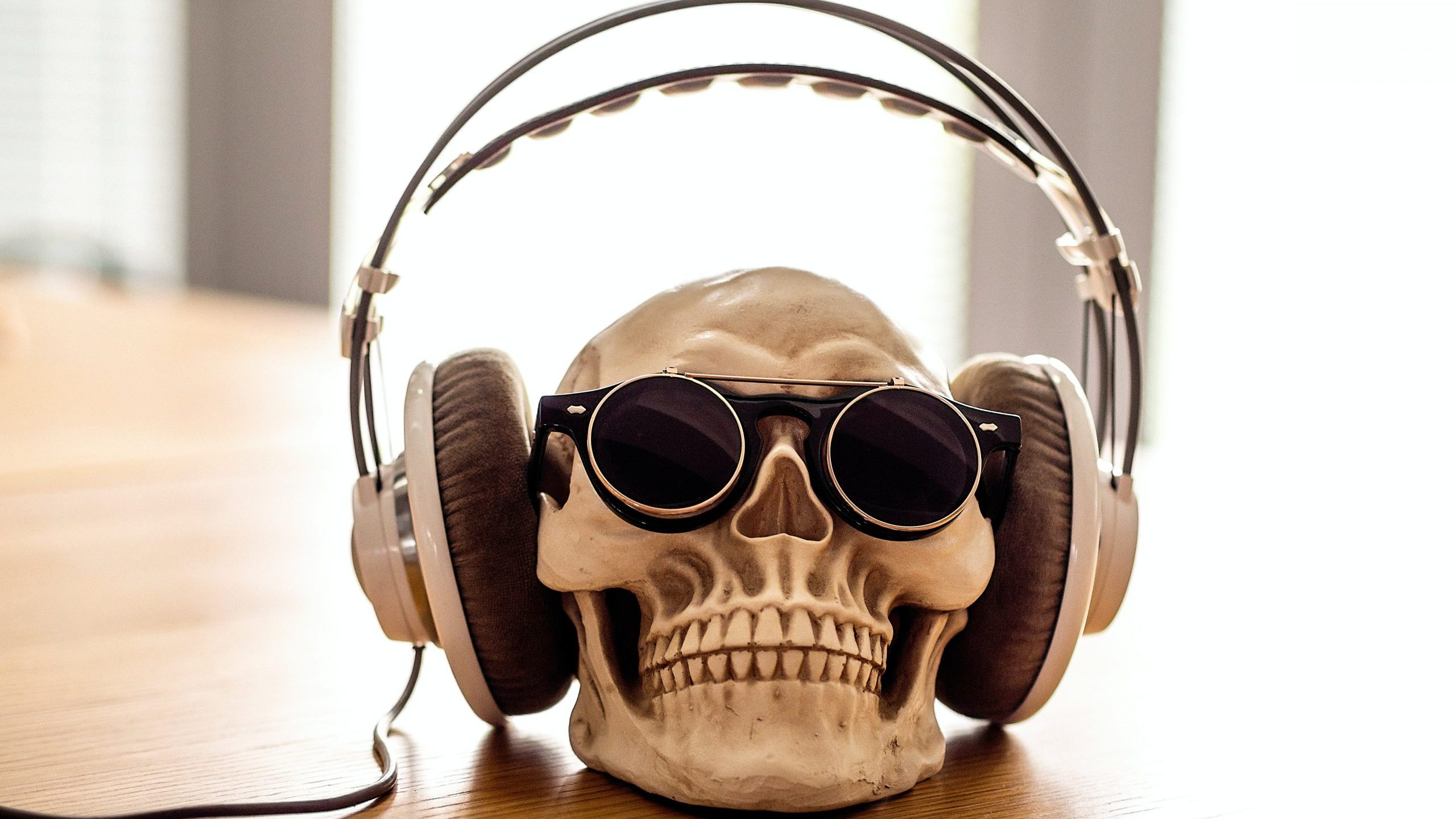 Human skull wearing headphones and dark glasses on a desk