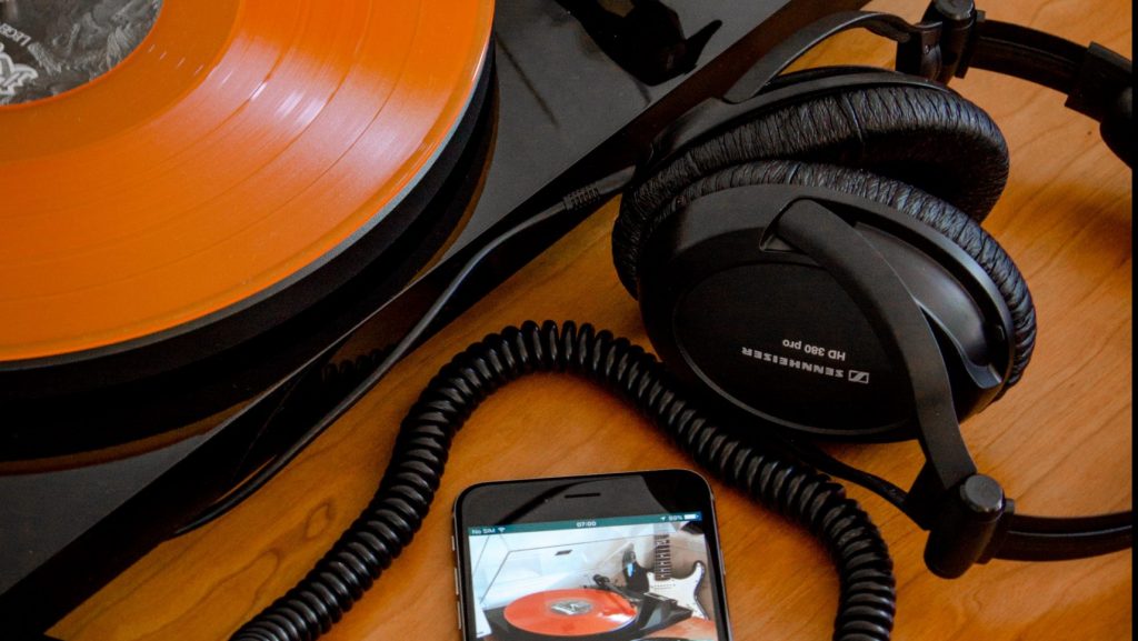 A turntable, smart phone and some headphones on a desk