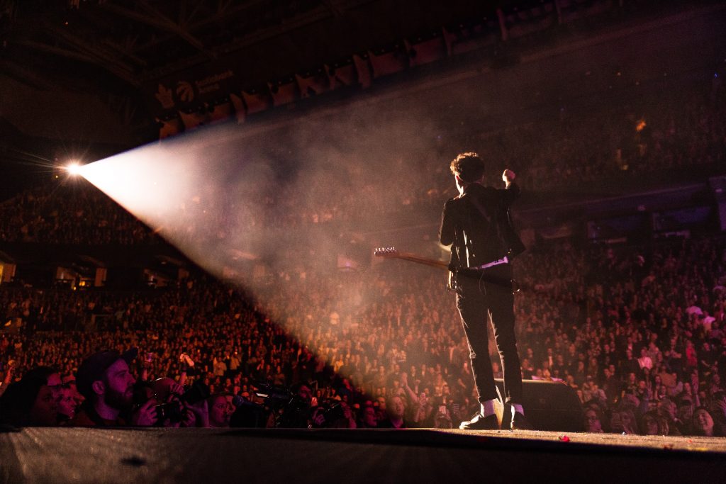 Musician standing before a large crowd.