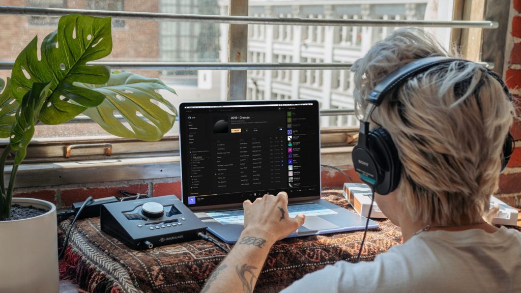 Person sits at a desk with a laptop based recording setup.
