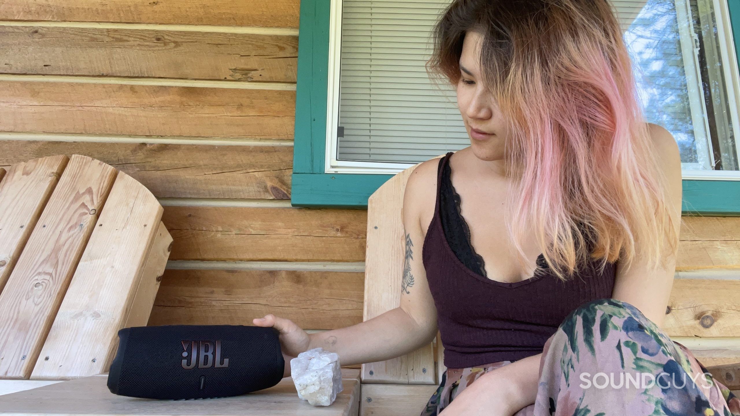 Une femme touche JBL Charge 5 en s'appuyant sur une table.