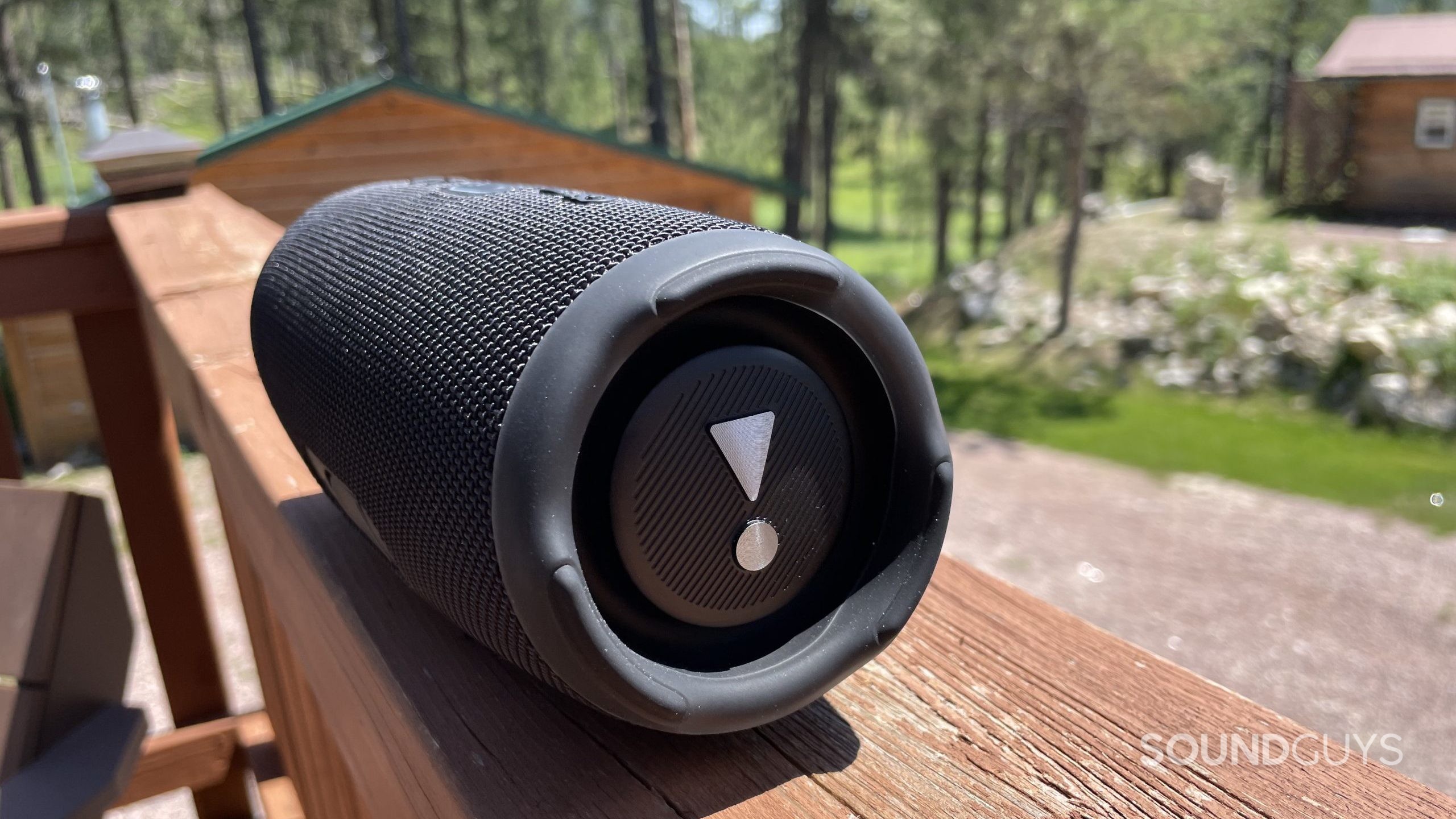 JBL Charge 5 resting on a balcony fence. The bass radiator is the focus of the photo.