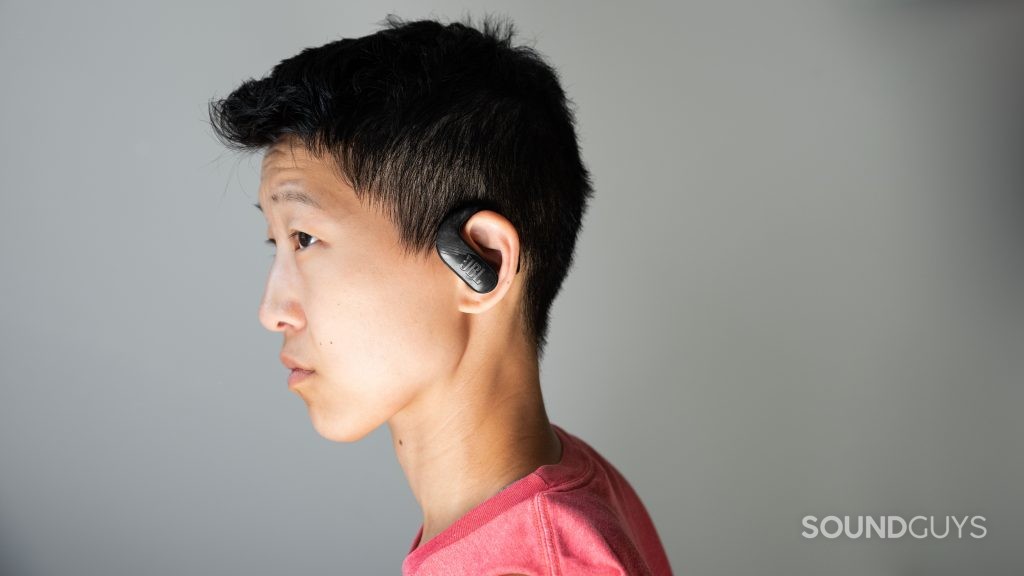 A woman wears the JBL ENDURANCE PEAK II true wireless workout earbuds in profile.