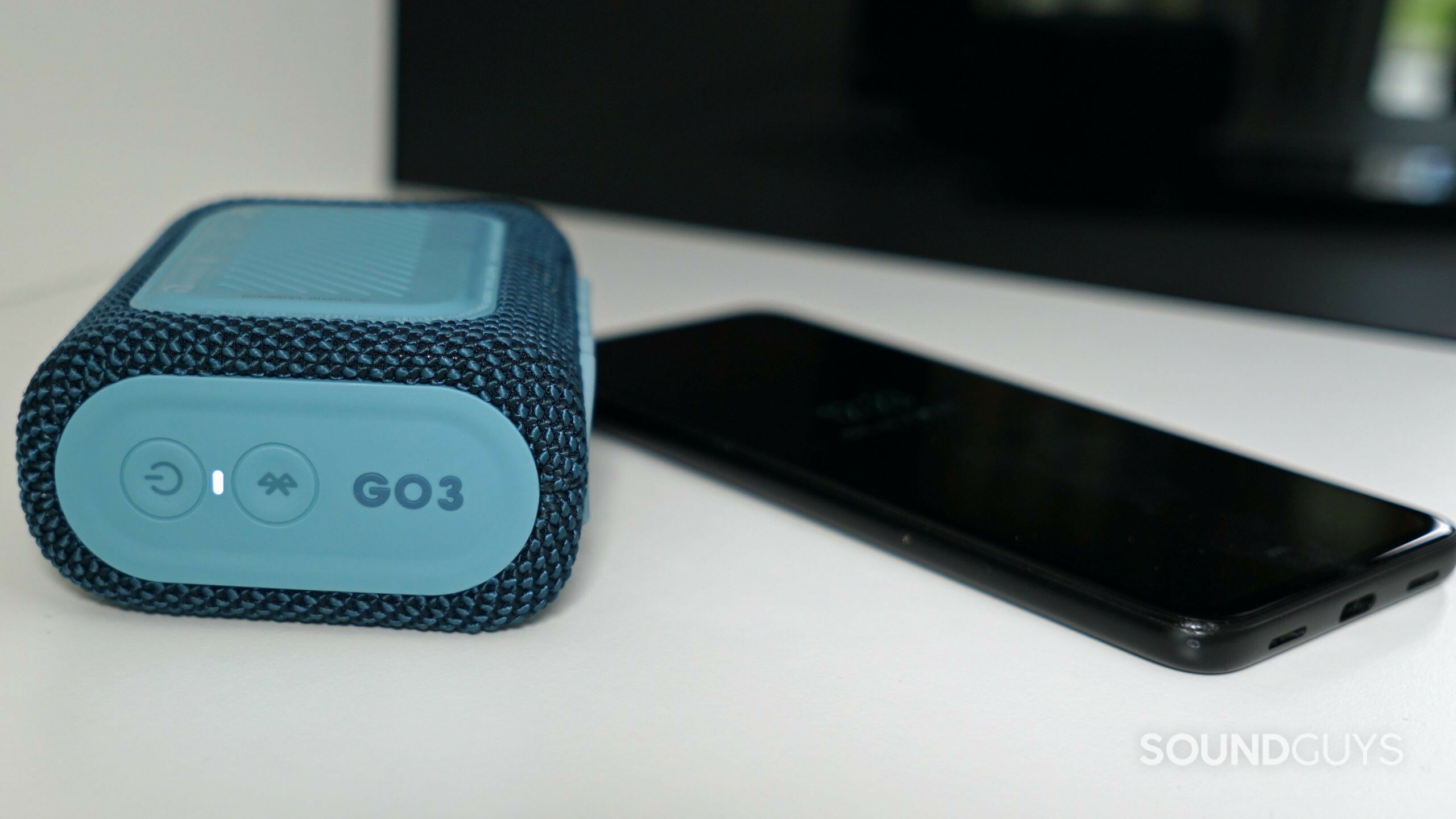 JBL-Go-3-Phone The JBL Go 3 lays on a white shelf paired to a Google Pixel 4a.