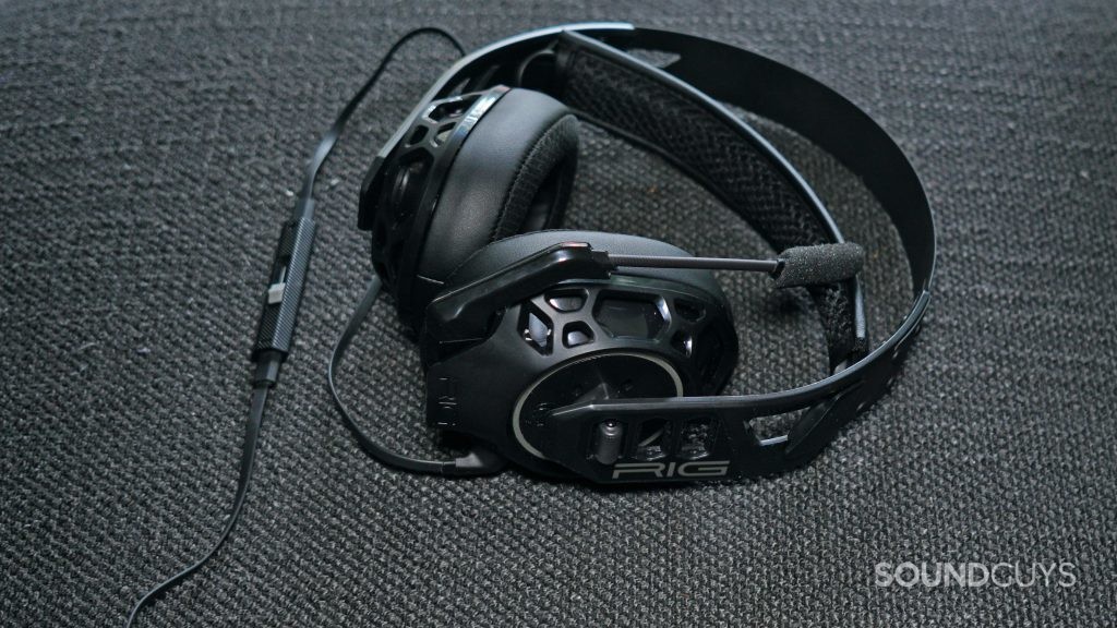 The Nacon RIG 500 Pro HC lays on a fabric surface, with its mic in the muted position and its in-line control unit visible.
