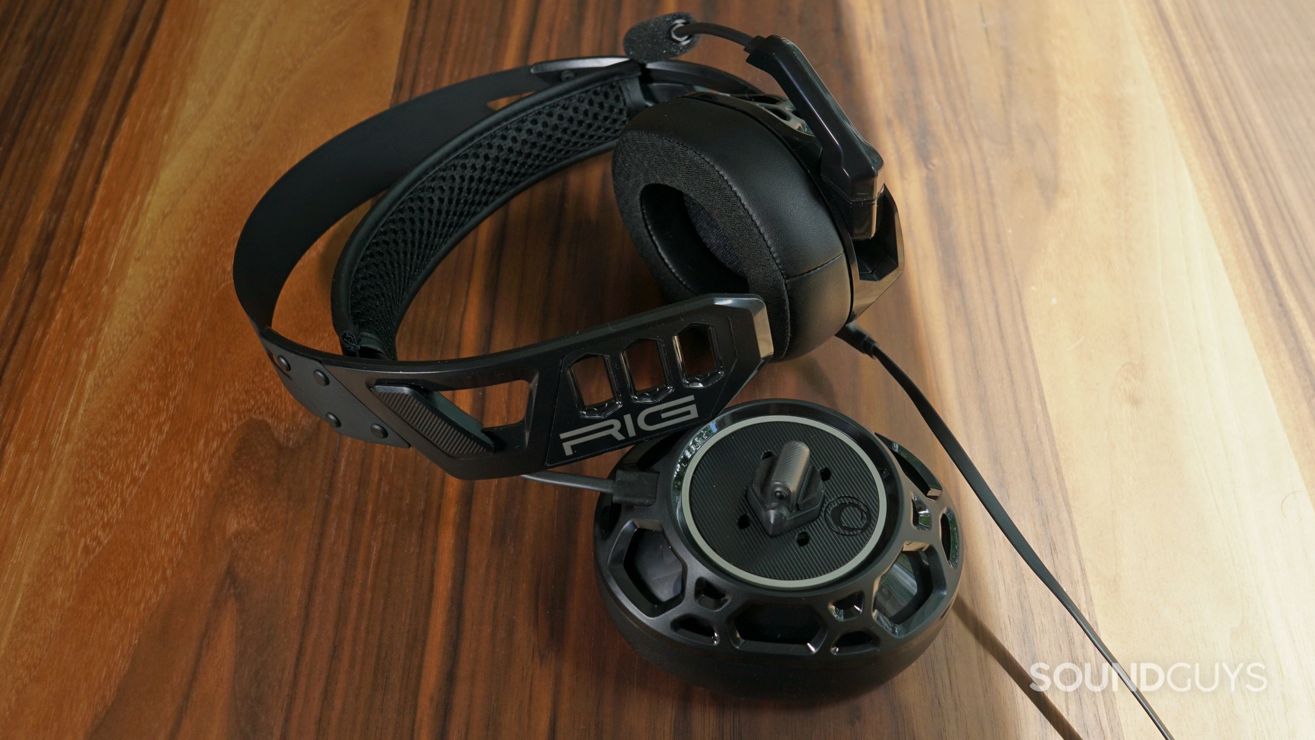 The Nacon RIG 500 Pro HC gaming headset lays on a wooden table with the right headphone detached.