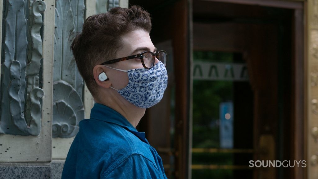 A man is outside a building wearing master & dynamic mw08 earphones.
