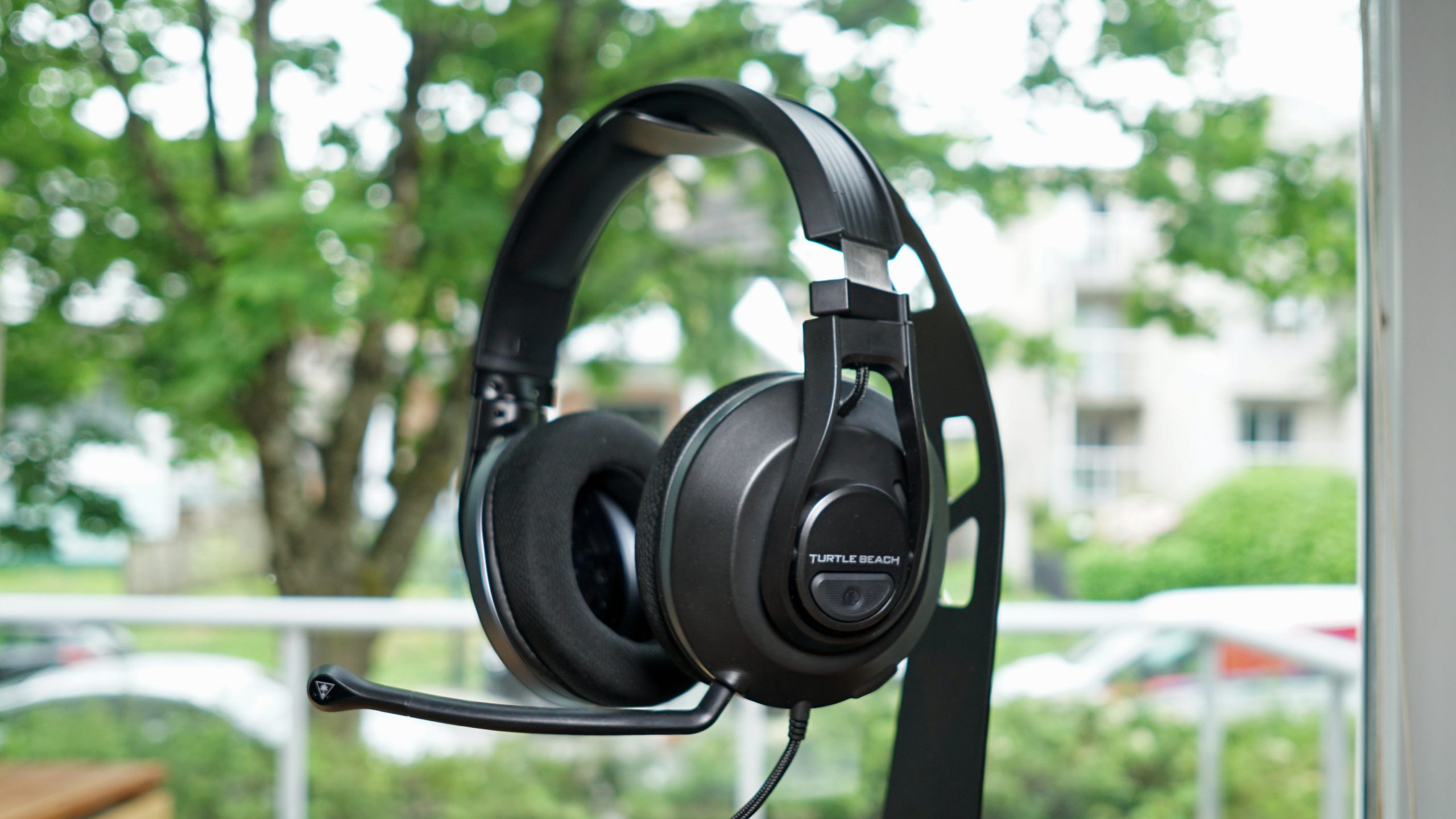 The Turtle Beach Recon 500 sits on a headphone stand in front of a window