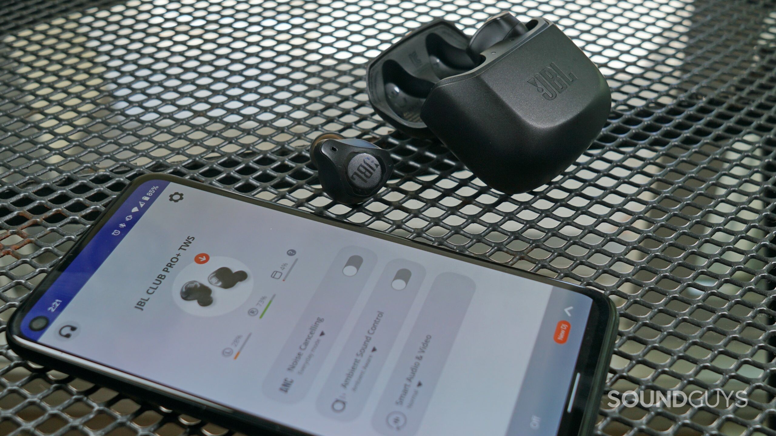 The JBL Club Pro + lays on a wire table next to a Google Pixel 4a running the JBL smart control app.
