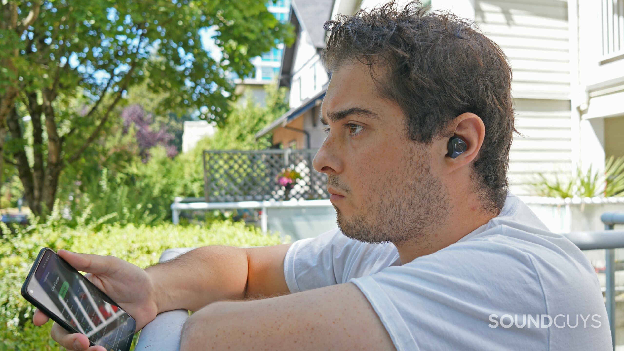 A man sits outside listening to the JBL Club Pro Plus paired to Google Pixel 4a