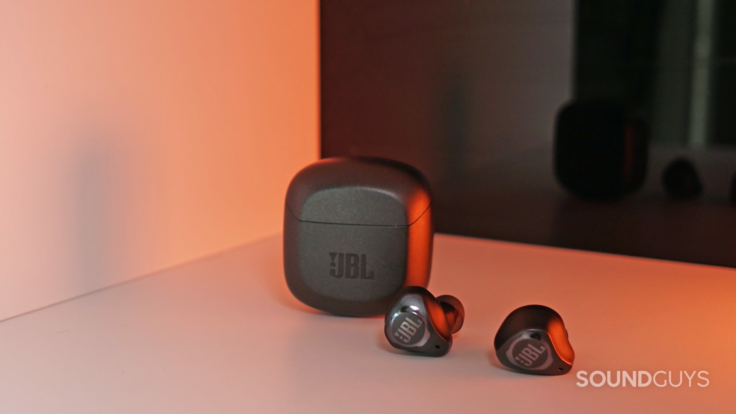 The JBL Club Pro Plus lays in front of its case on a white shelf