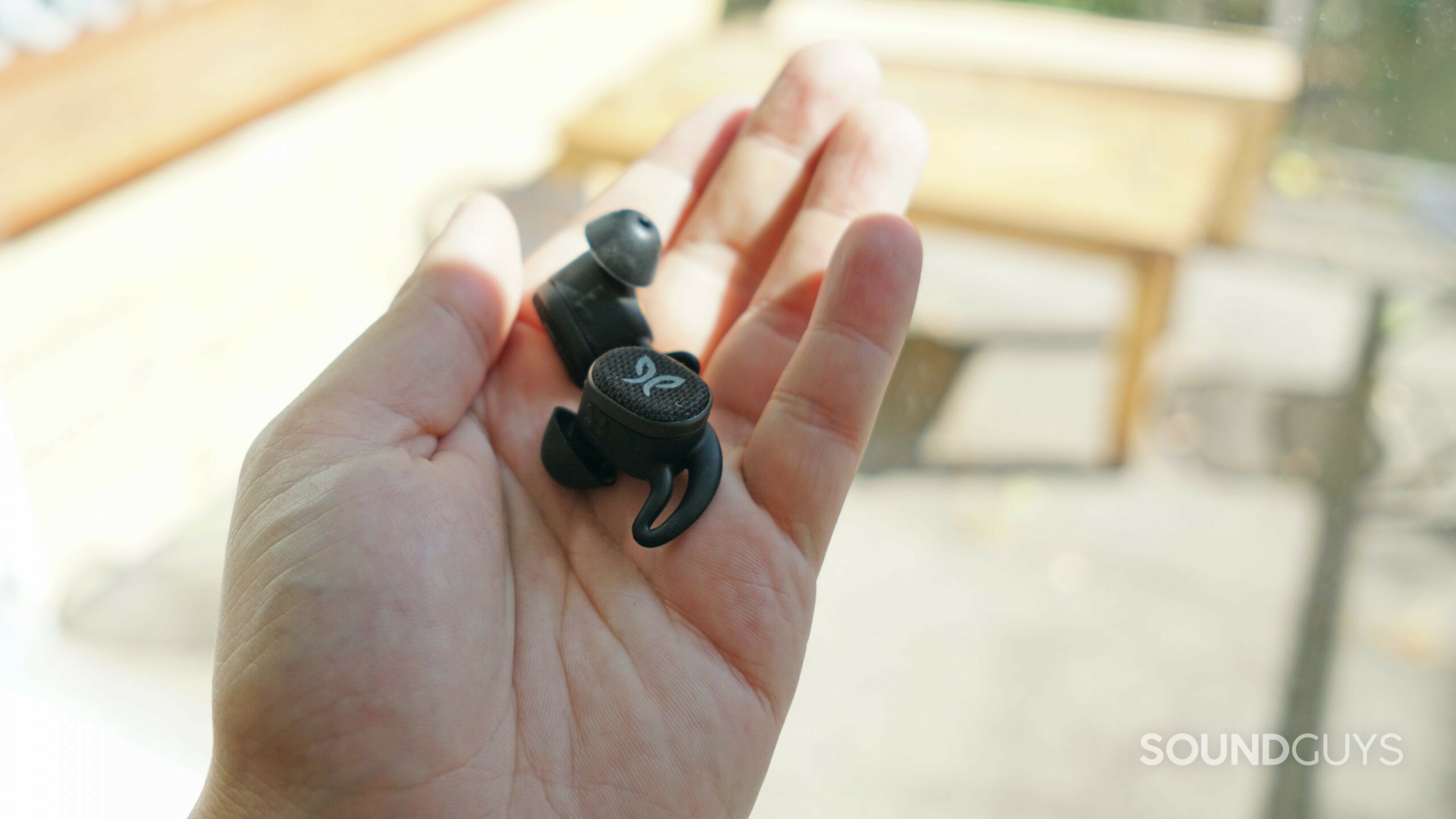 Jaybird Vista 2 earbuds in hand outdoors.